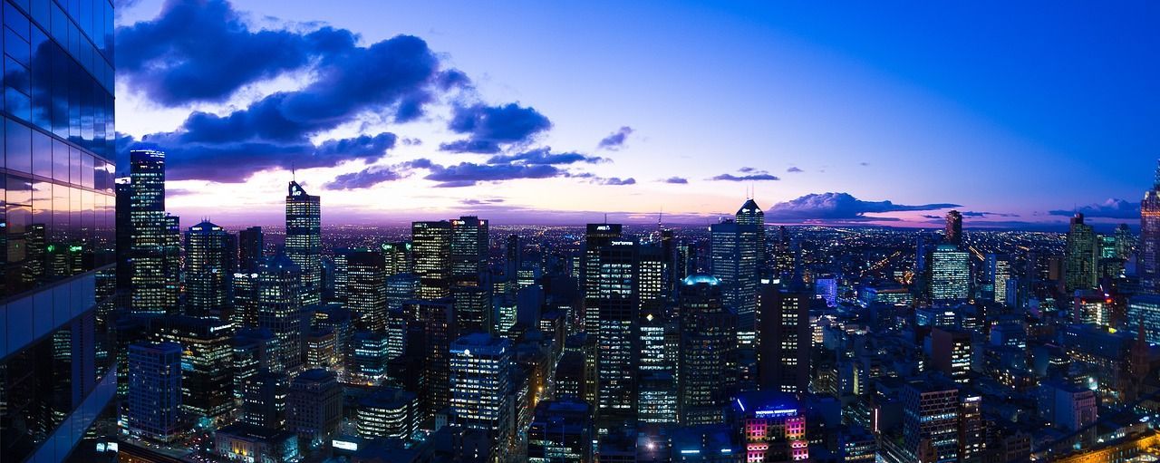 An aerial view of a city at night with a sunset in the background.