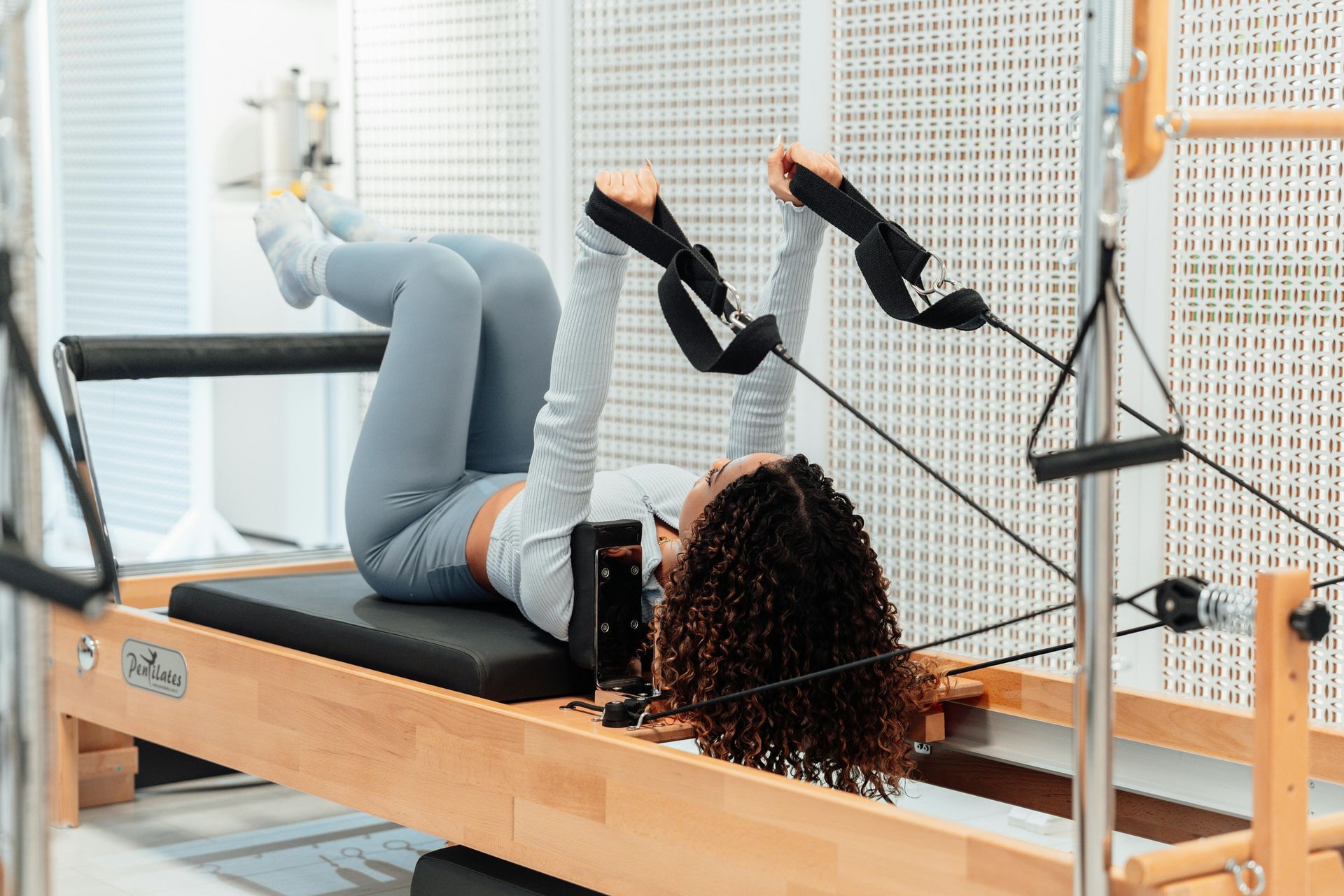 A woman is laying on a pilates machine in a gym.