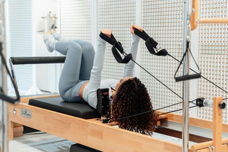 A woman is laying on a pilates machine in a gym.