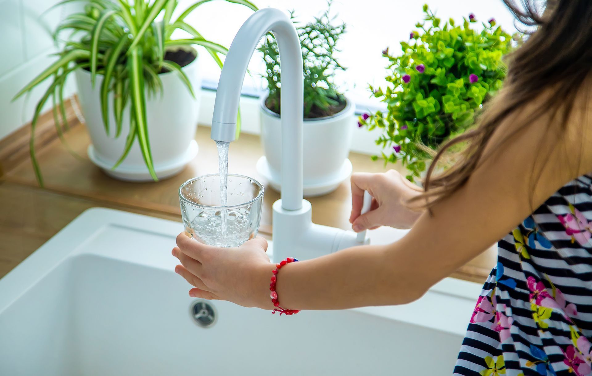 Children picks up a glass of water from the tap. Children picks up a glass of water from the tap.