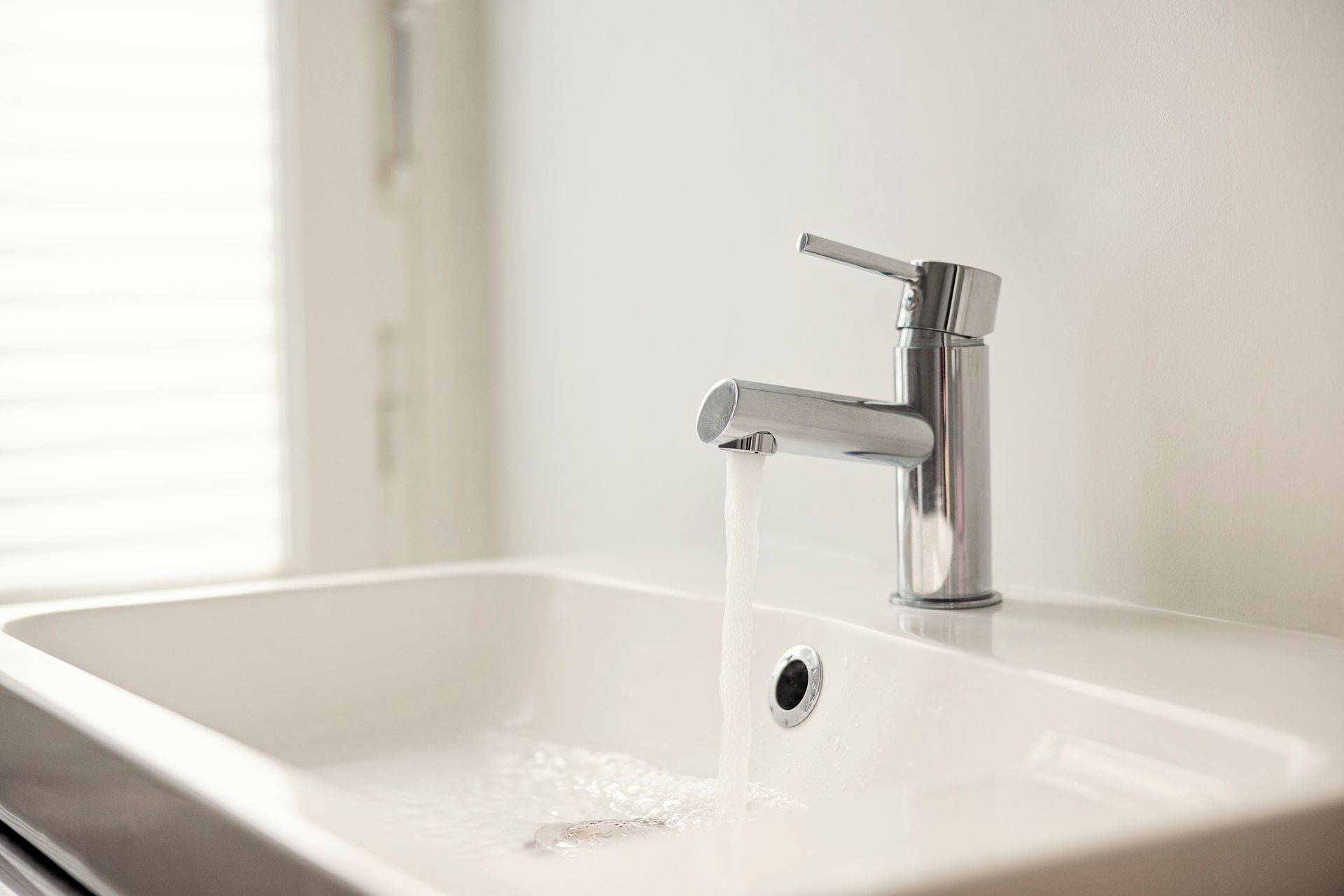 Close-up of water pouring from a sink faucet.