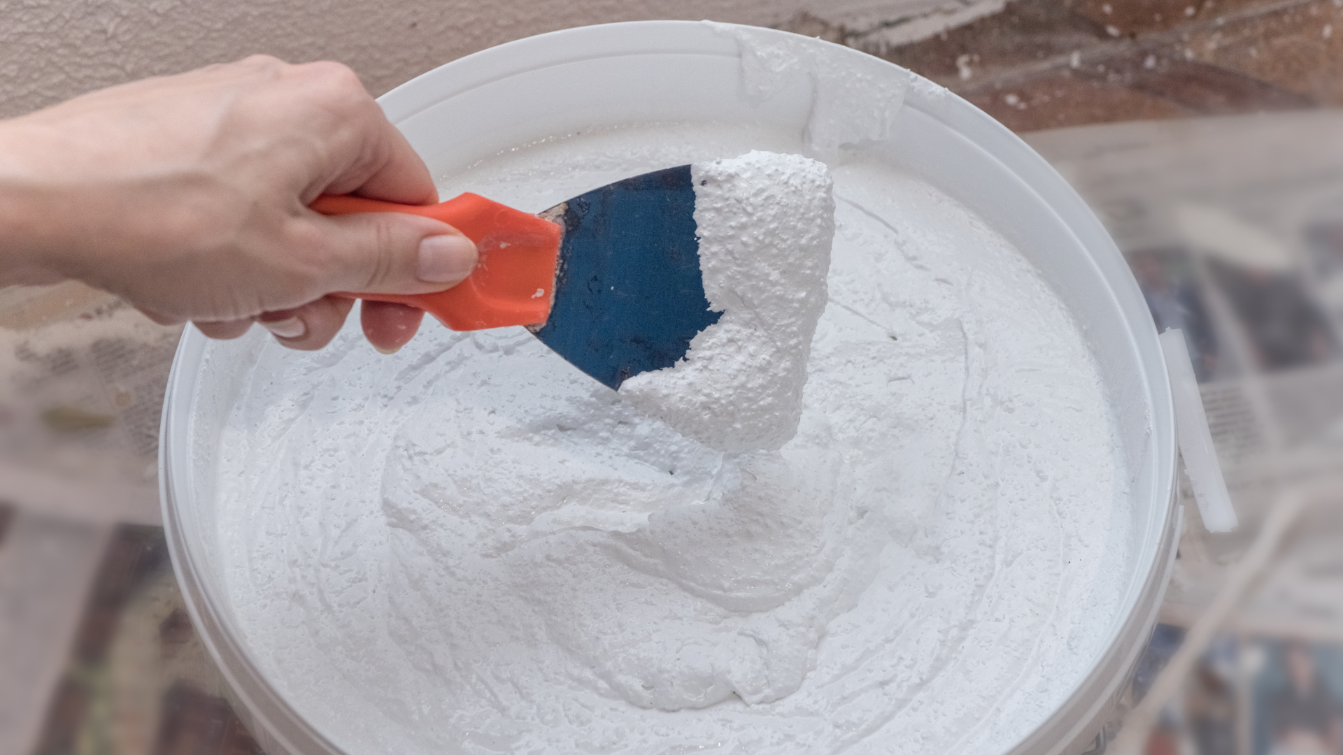 A man wearing a hard hat and gloves is working on an air conditioner.