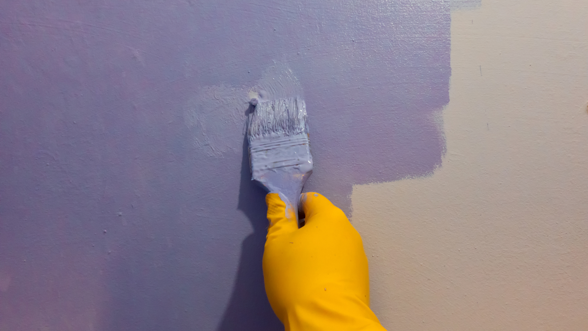 A man wearing a hard hat and gloves is working on an air conditioner.