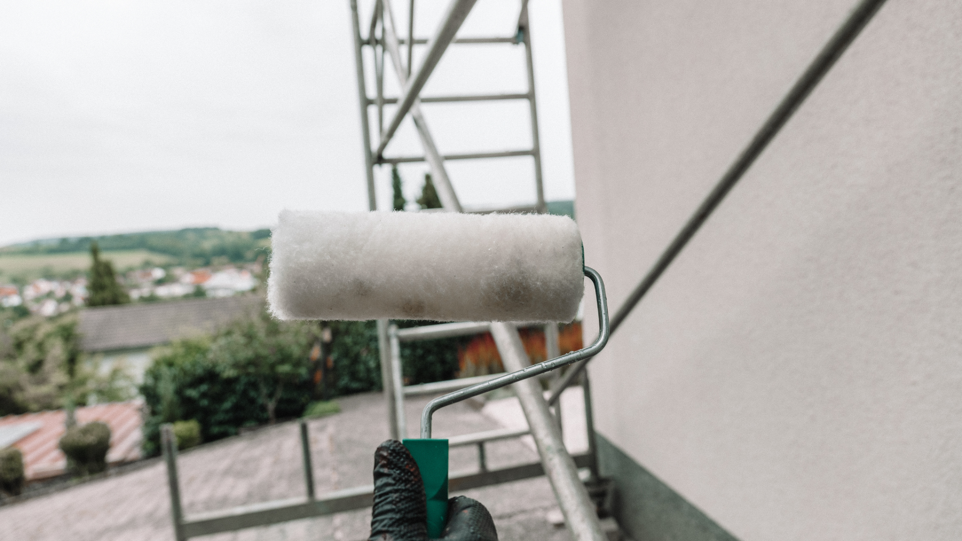 A wooden fence surrounds a dry grassy field with mountains in the background.