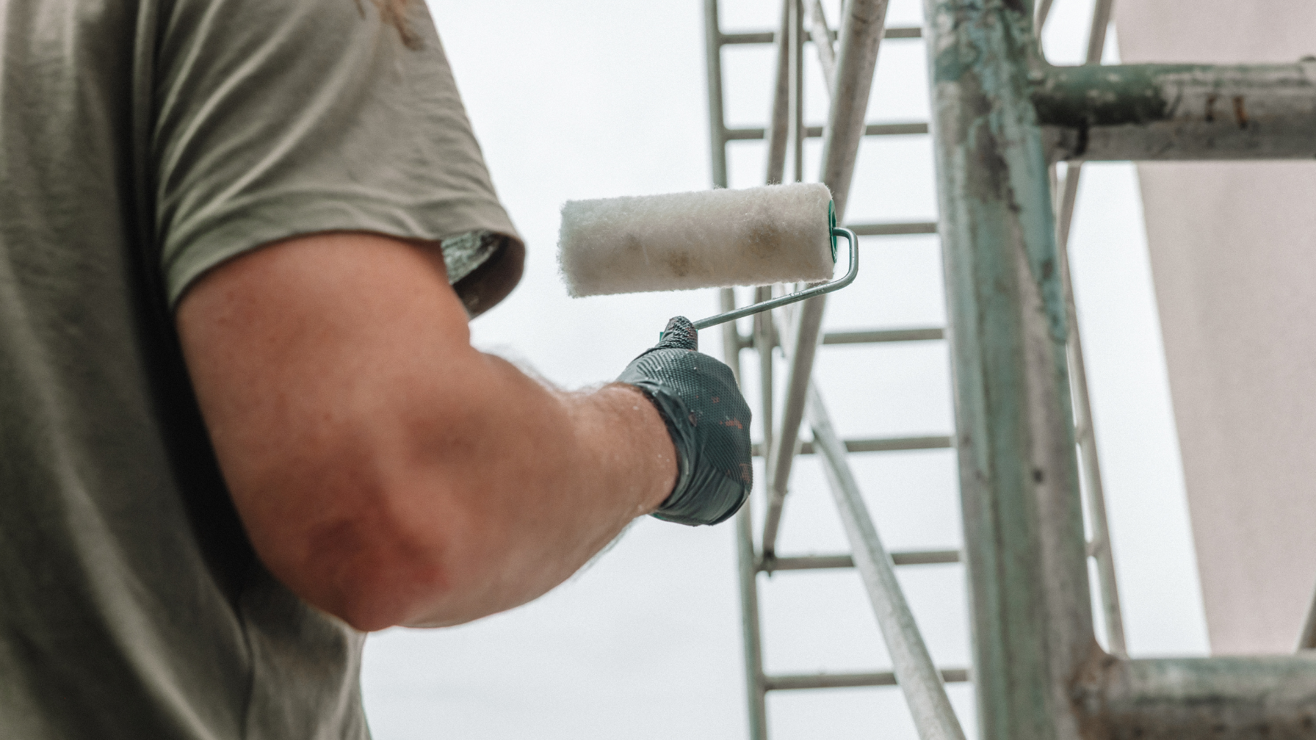 A man is installing an air conditioner on the side of a building.