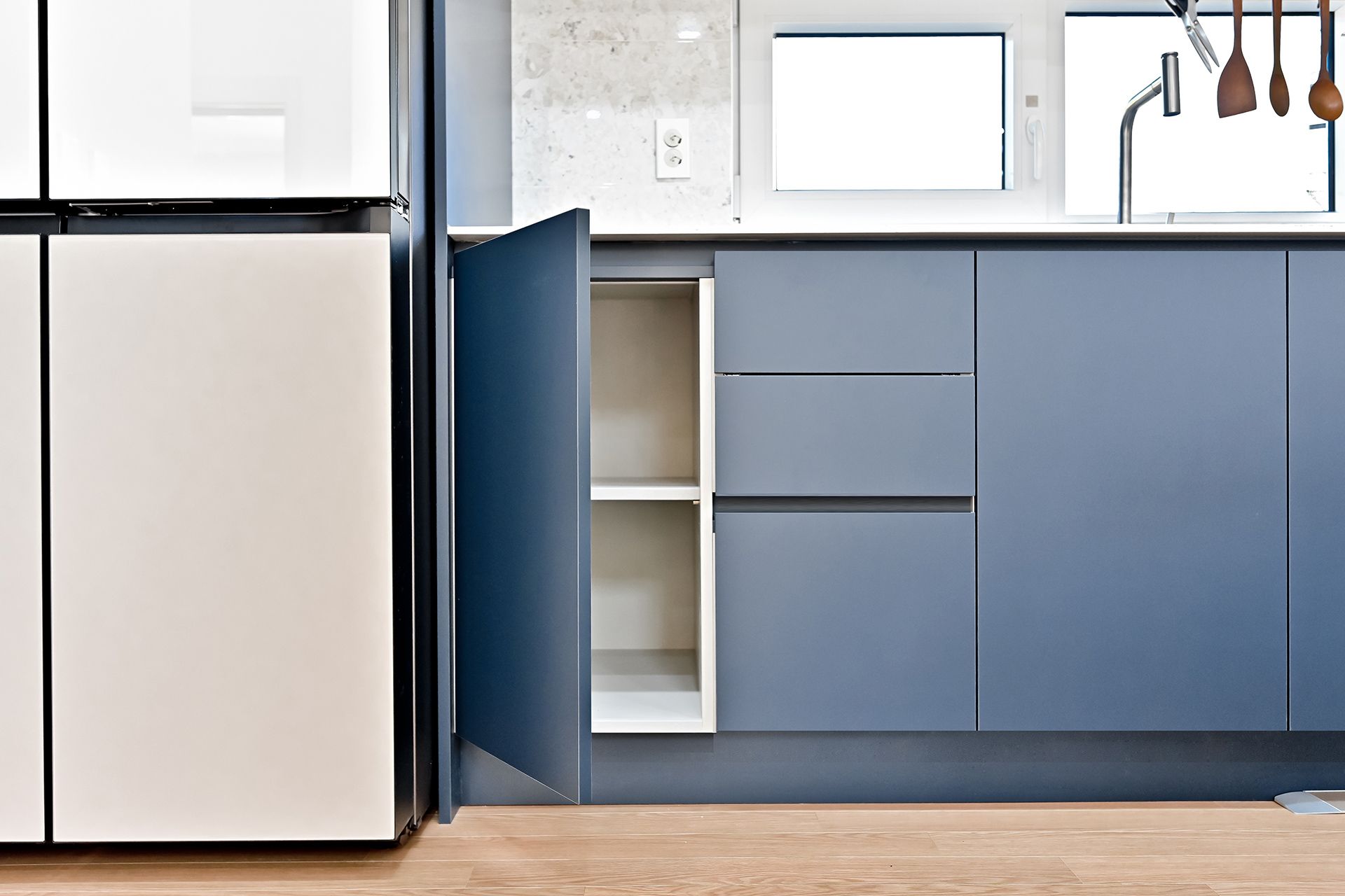 A kitchen with blue cabinets and a white refrigerator.