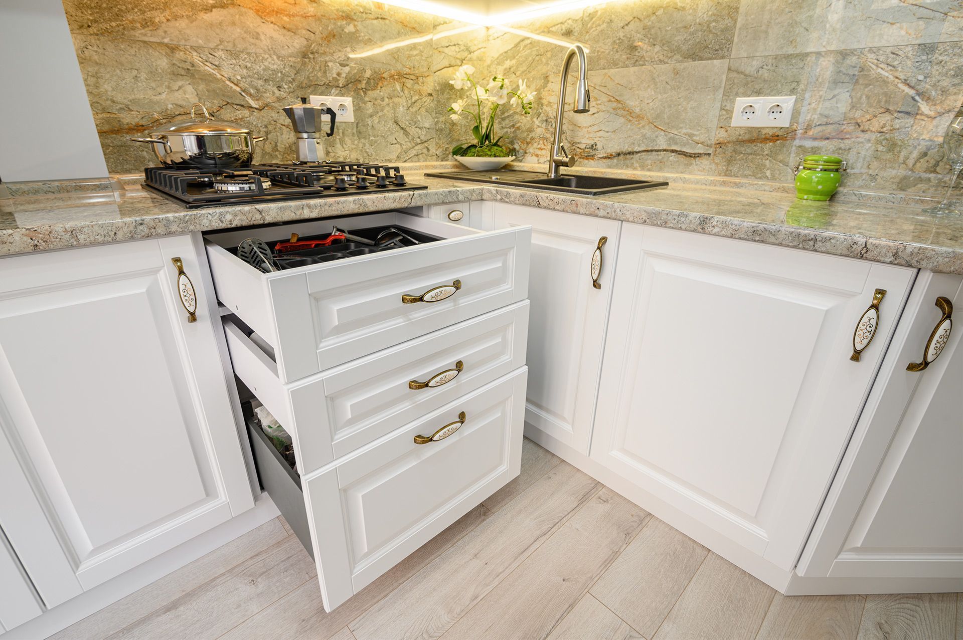 A kitchen with white cabinets and a stove with drawers open.