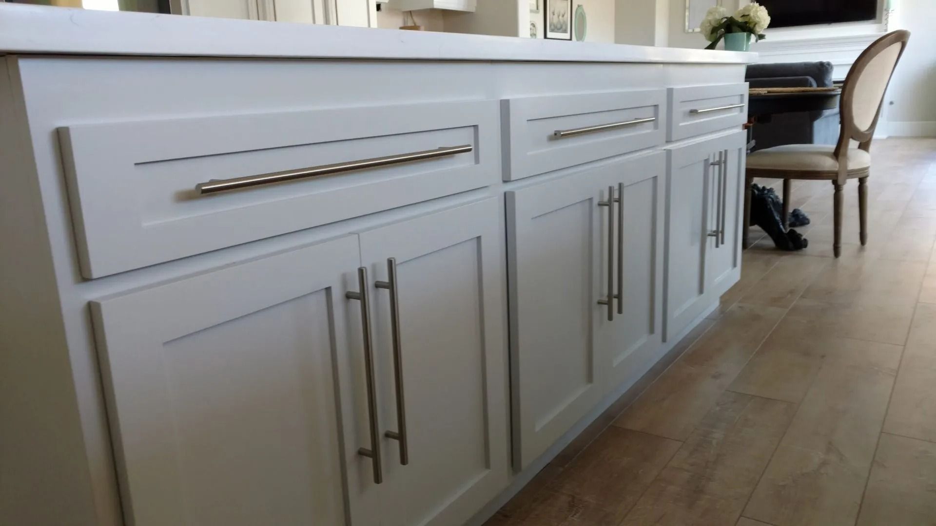 A kitchen with white cabinets and stainless steel handles
