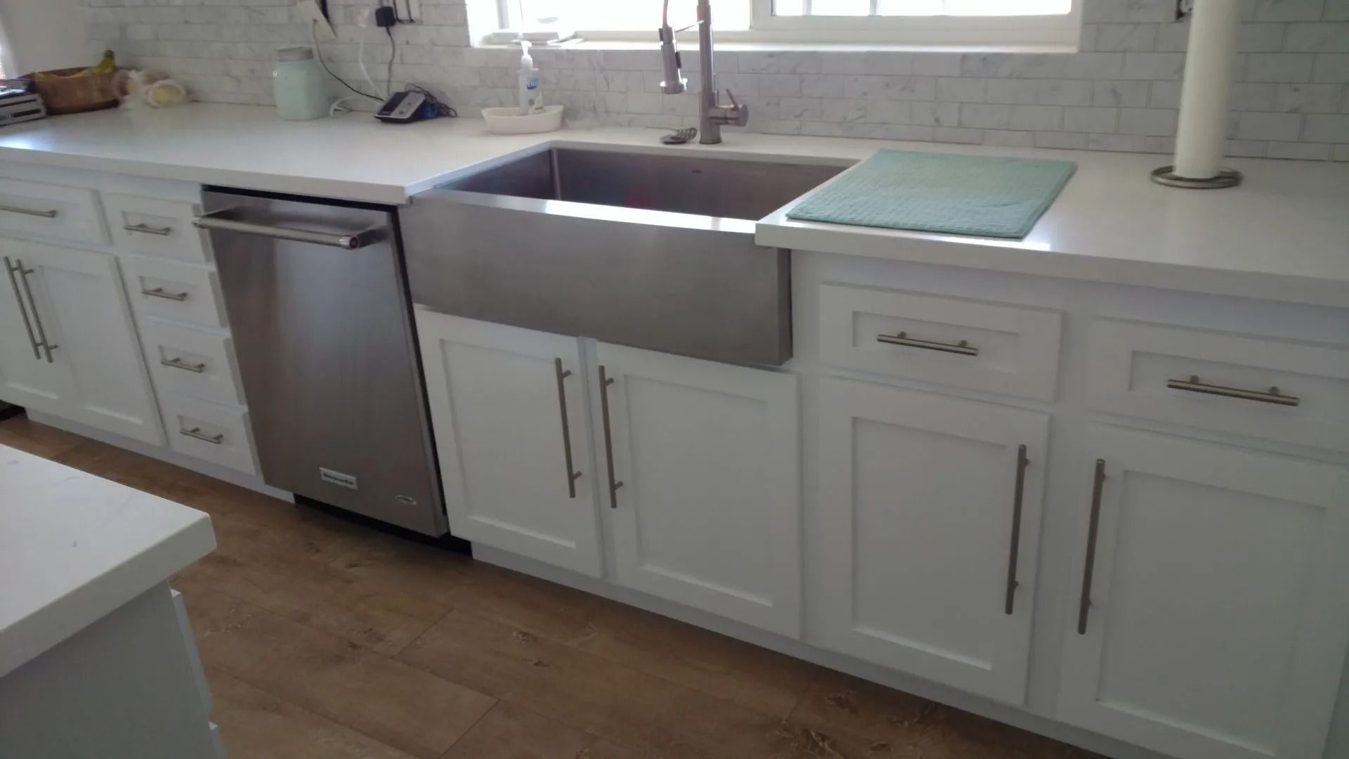 A kitchen with white cabinets , a stainless steel sink , and a dishwasher.