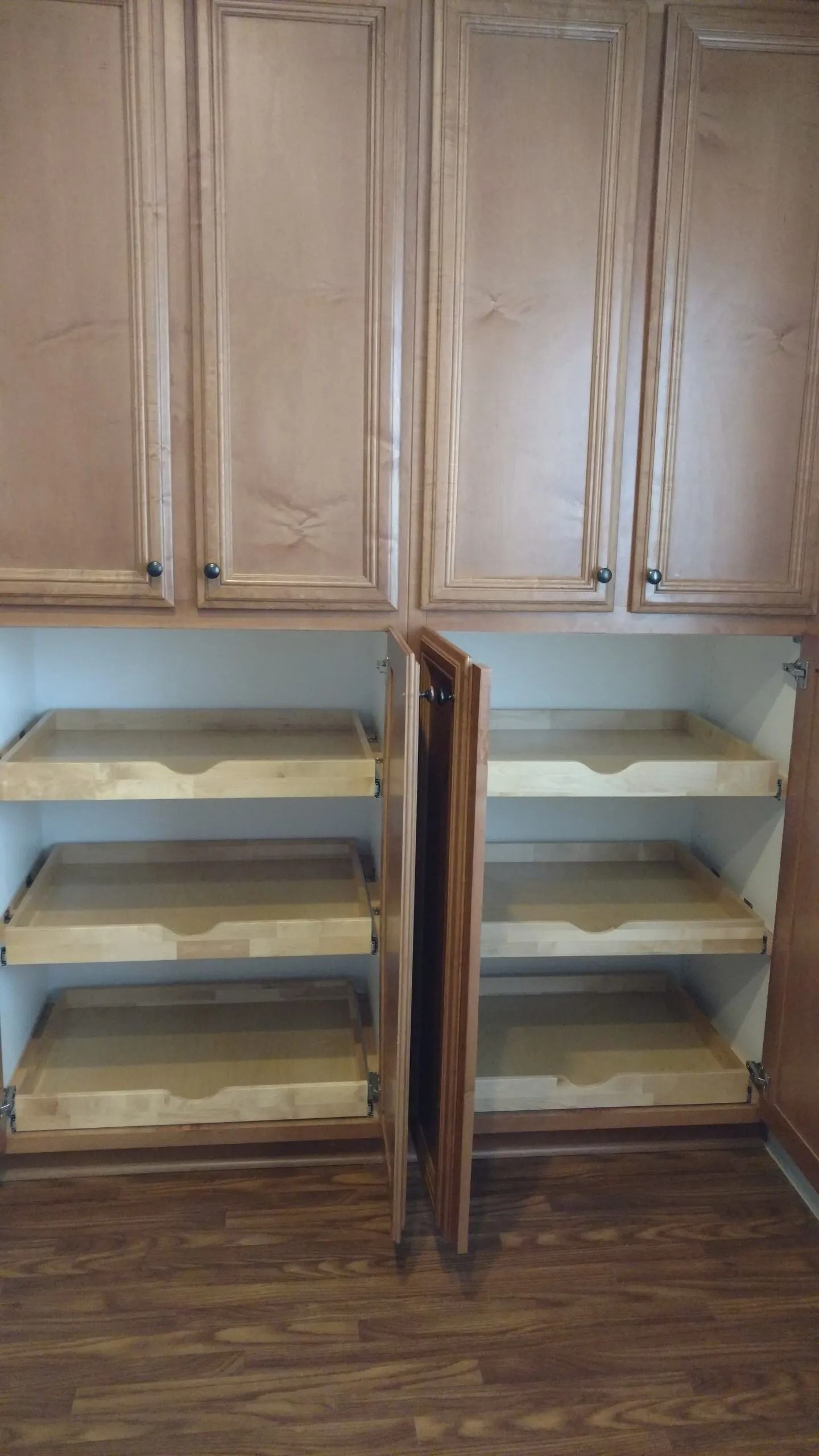 A kitchen with wooden cabinets and shelves and a wooden floor.