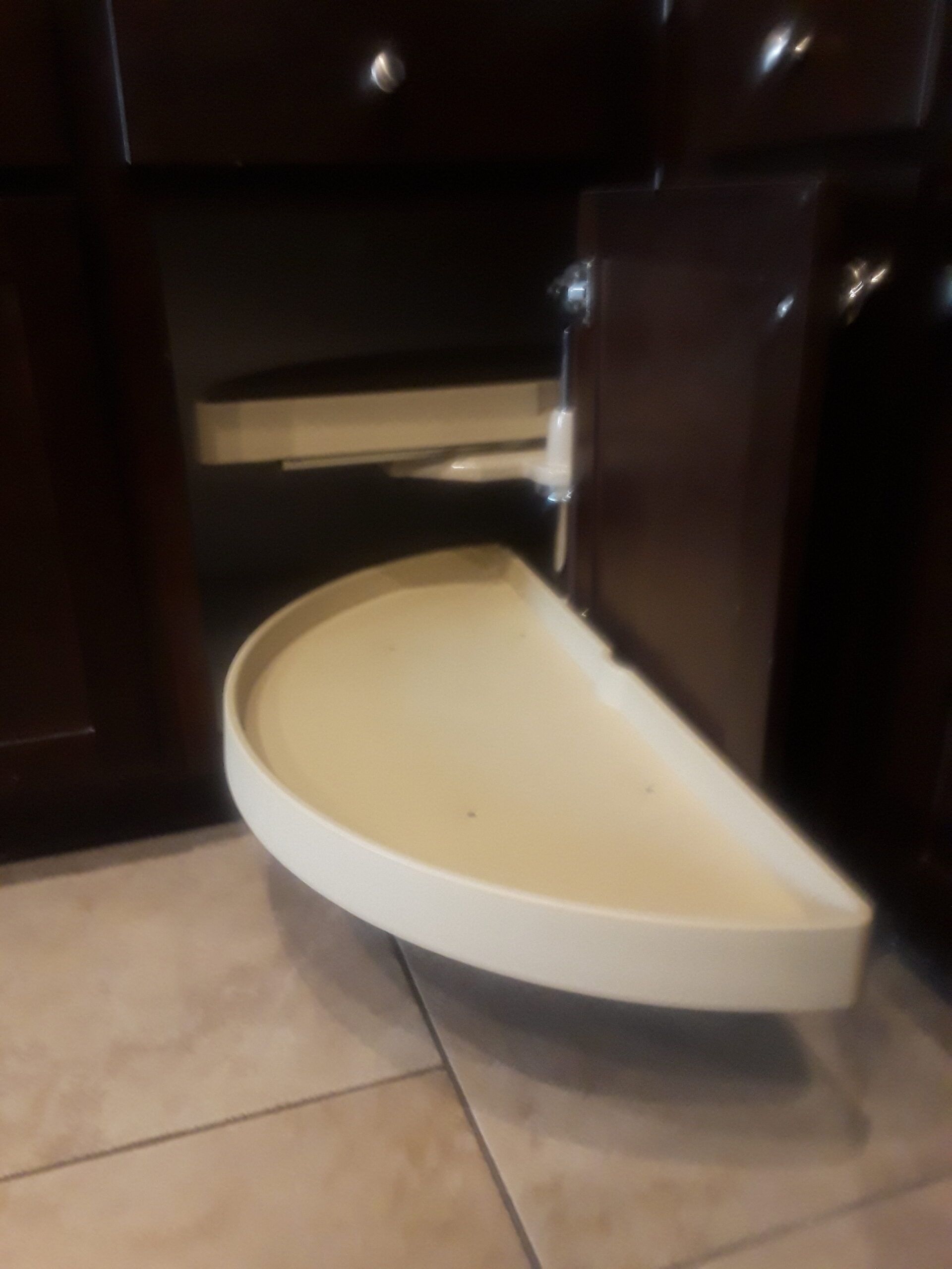 A white tray is sitting on a tiled floor in a kitchen