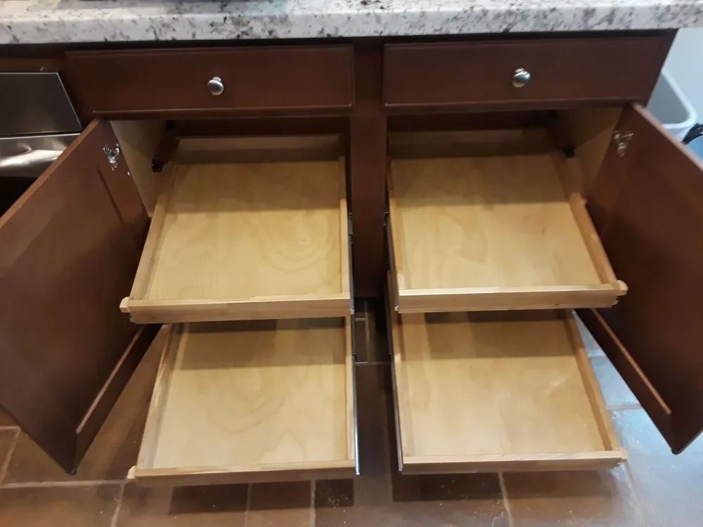 A kitchen cabinet with two drawers pulled out of it