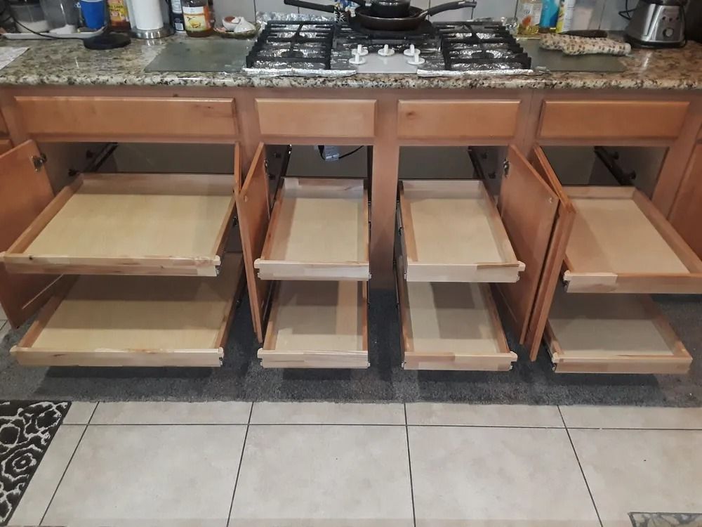 A kitchen with wooden cabinets and drawers and a stove top oven.