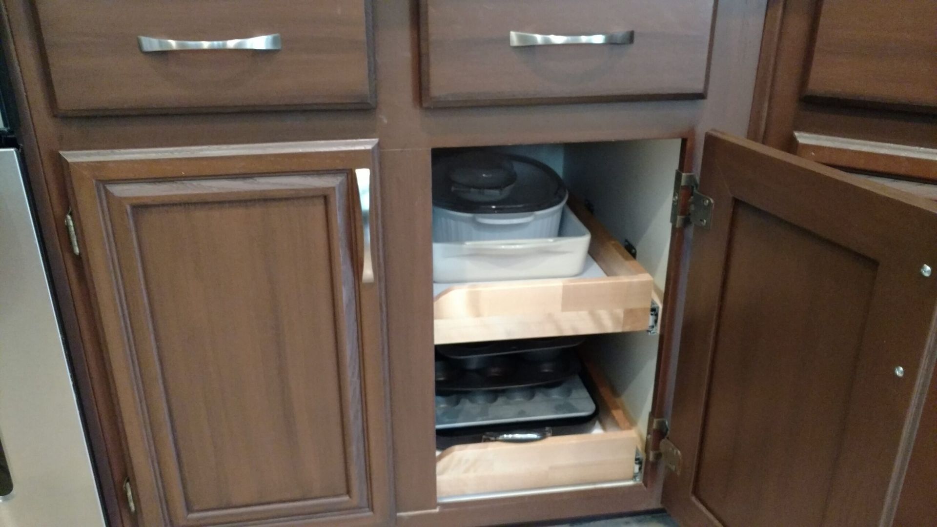 A kitchen cabinet with a pot and pans inside of it.