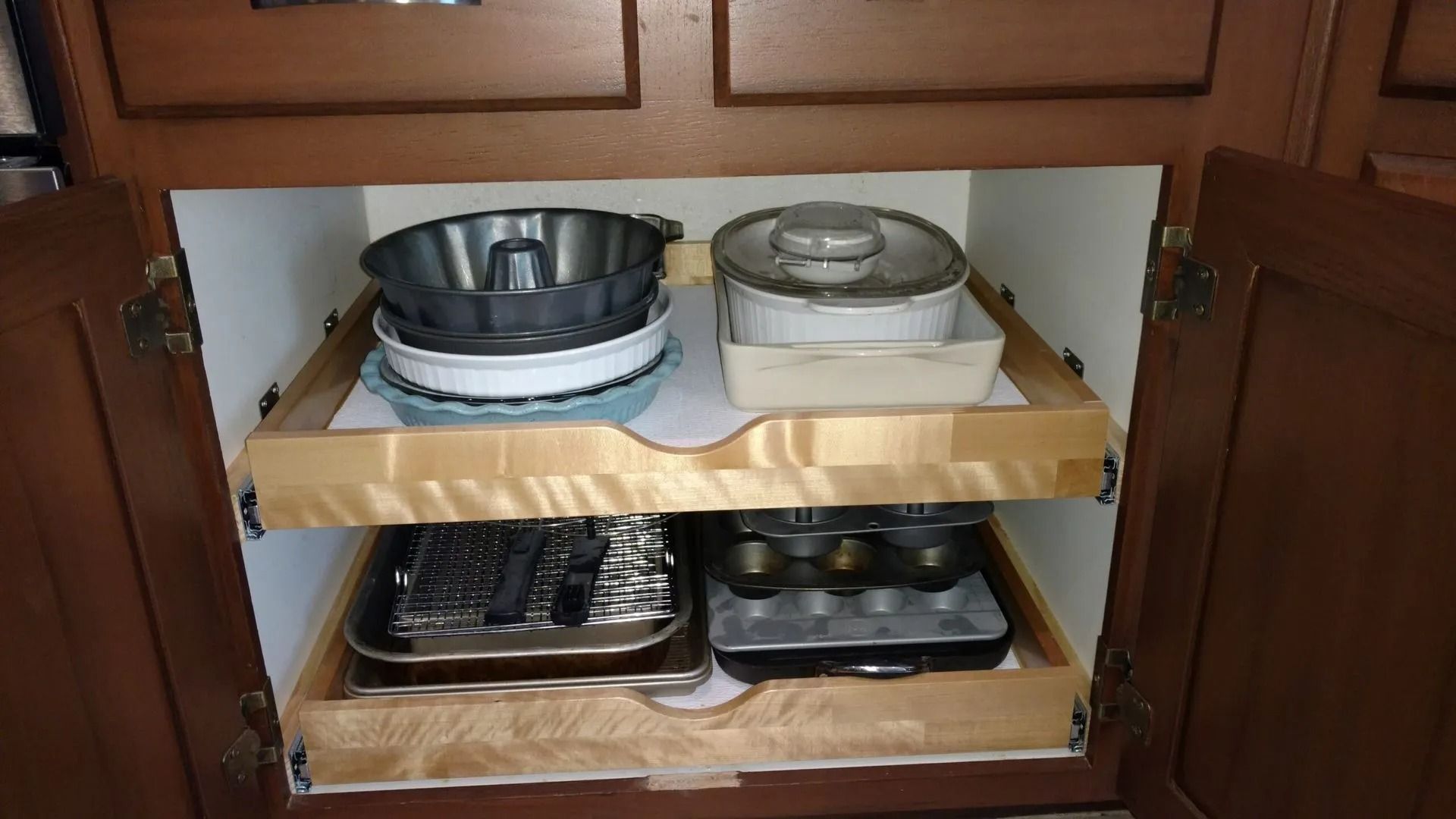 A kitchen cabinet with a pull out shelf filled with pots and pans