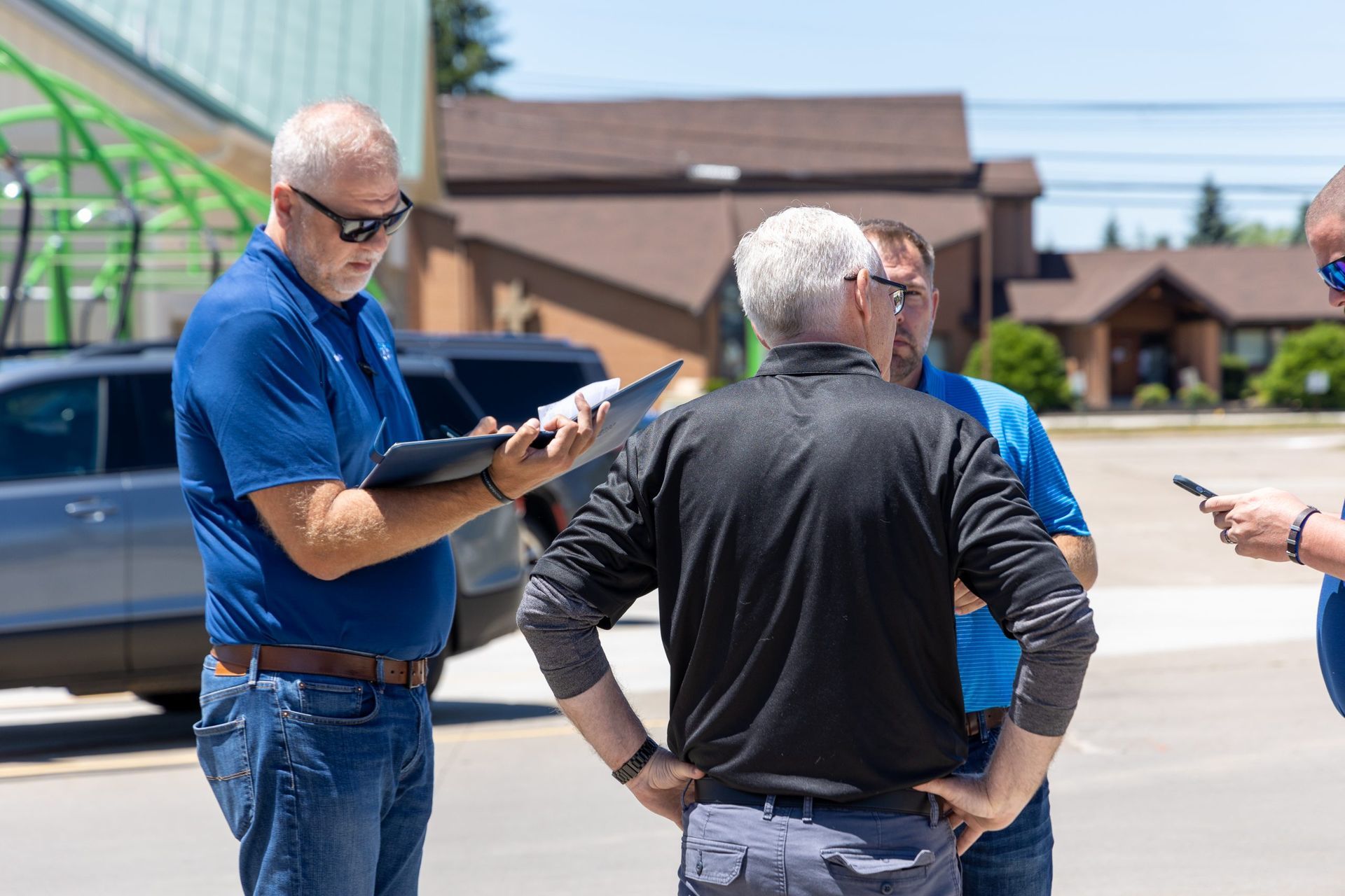 A group of men are standing in a parking lot talking to each other.