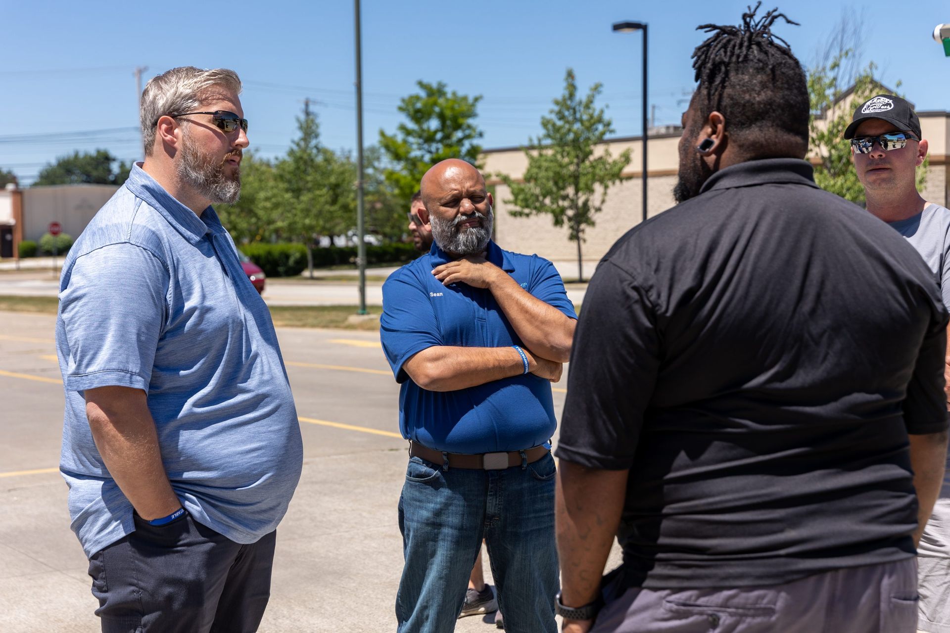 A group of men are standing in a parking lot talking to each other.