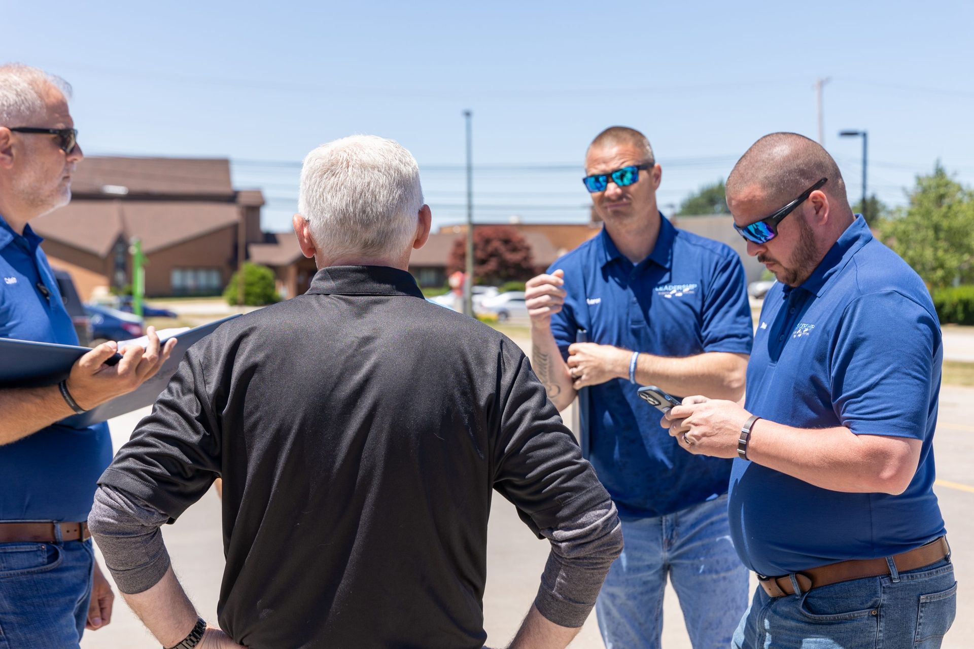 A group of men are standing in a parking lot talking to each other.