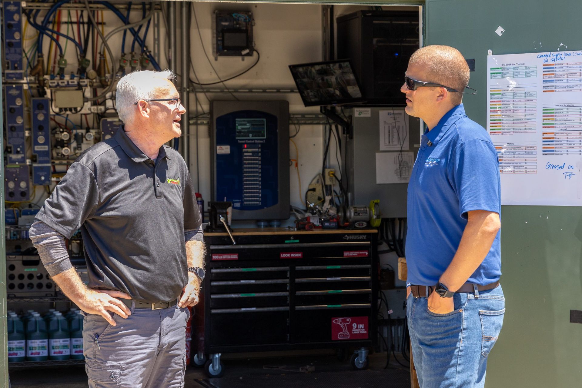 Two men are standing next to each other in a room and talking.