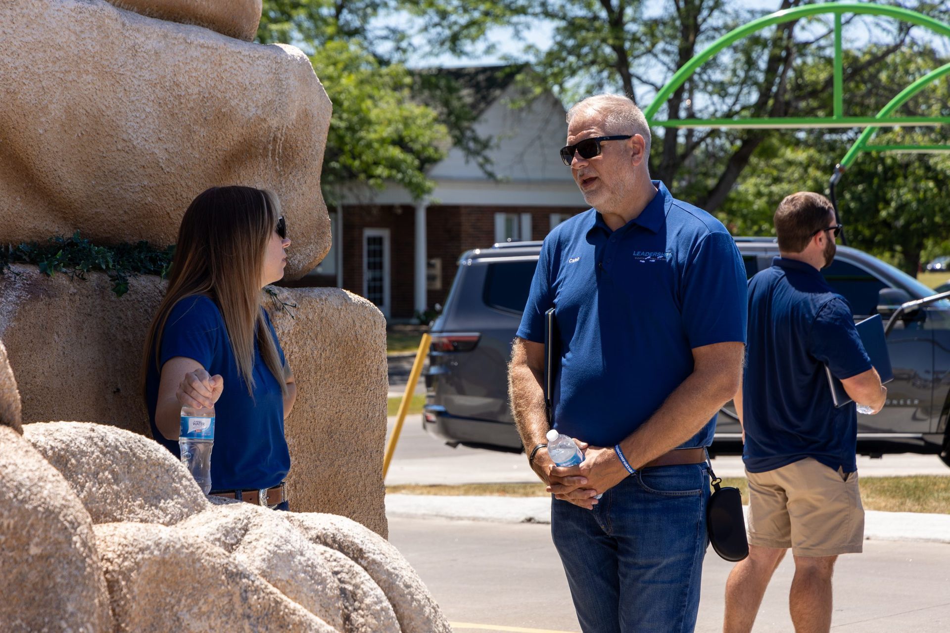 A group of people are standing on the side of the road talking to each other.