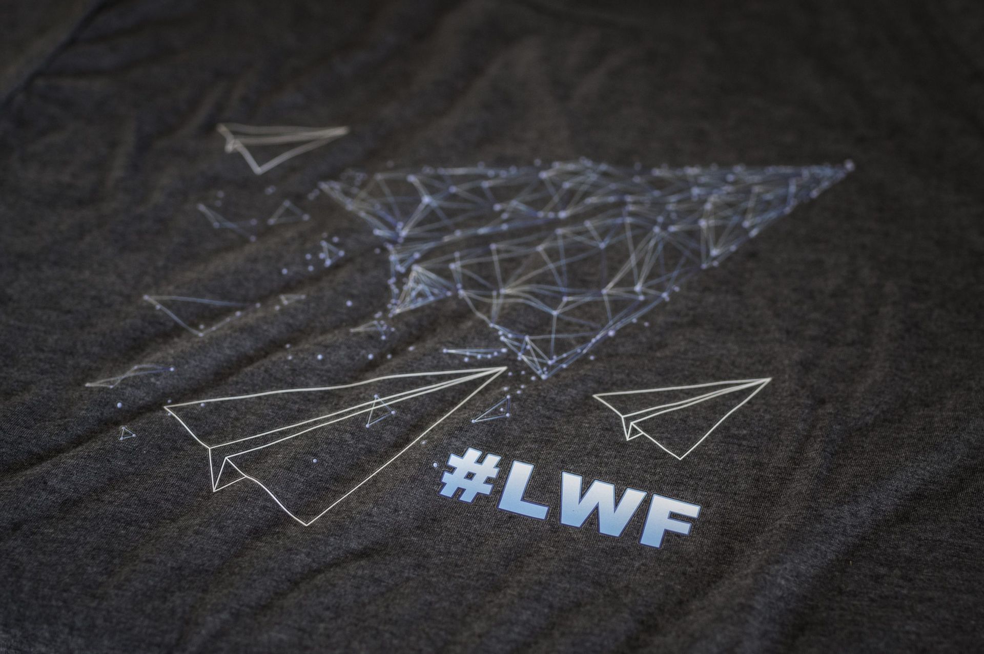 A black t-shirt with a paper airplane and the hashtag #lwf on it