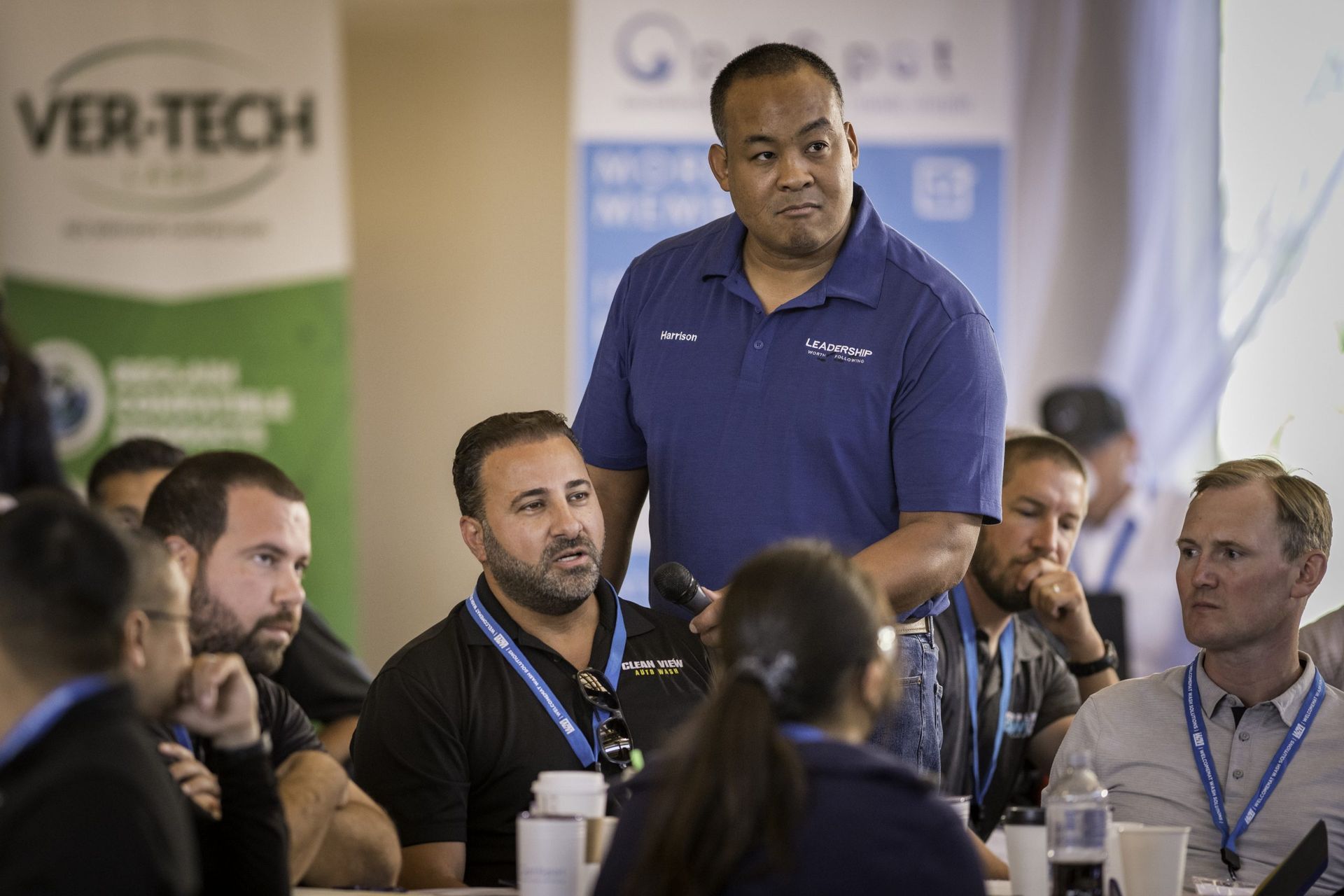 A man is talking to a group of people sitting at a table.