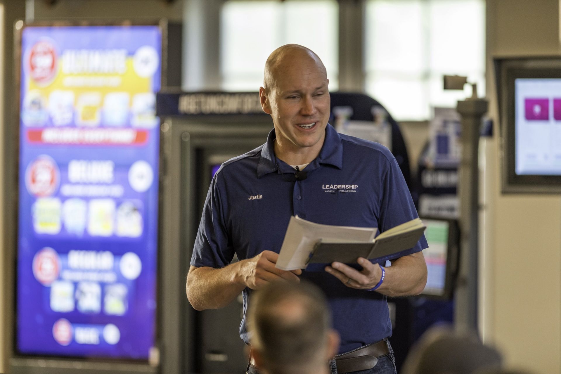 A man is reading a book while standing in front of a group of people.