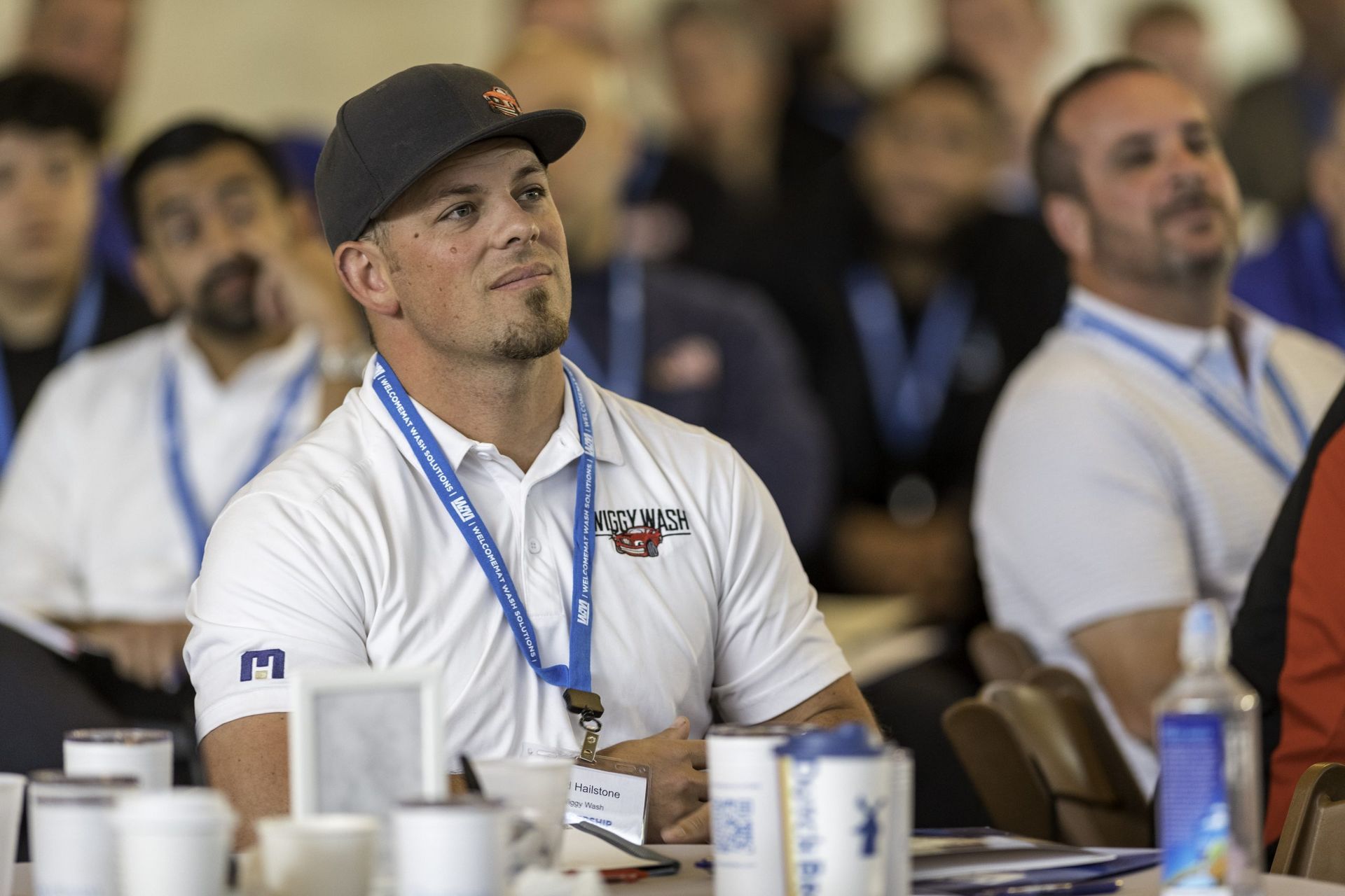 A man wearing a hat is sitting at a table with other people.