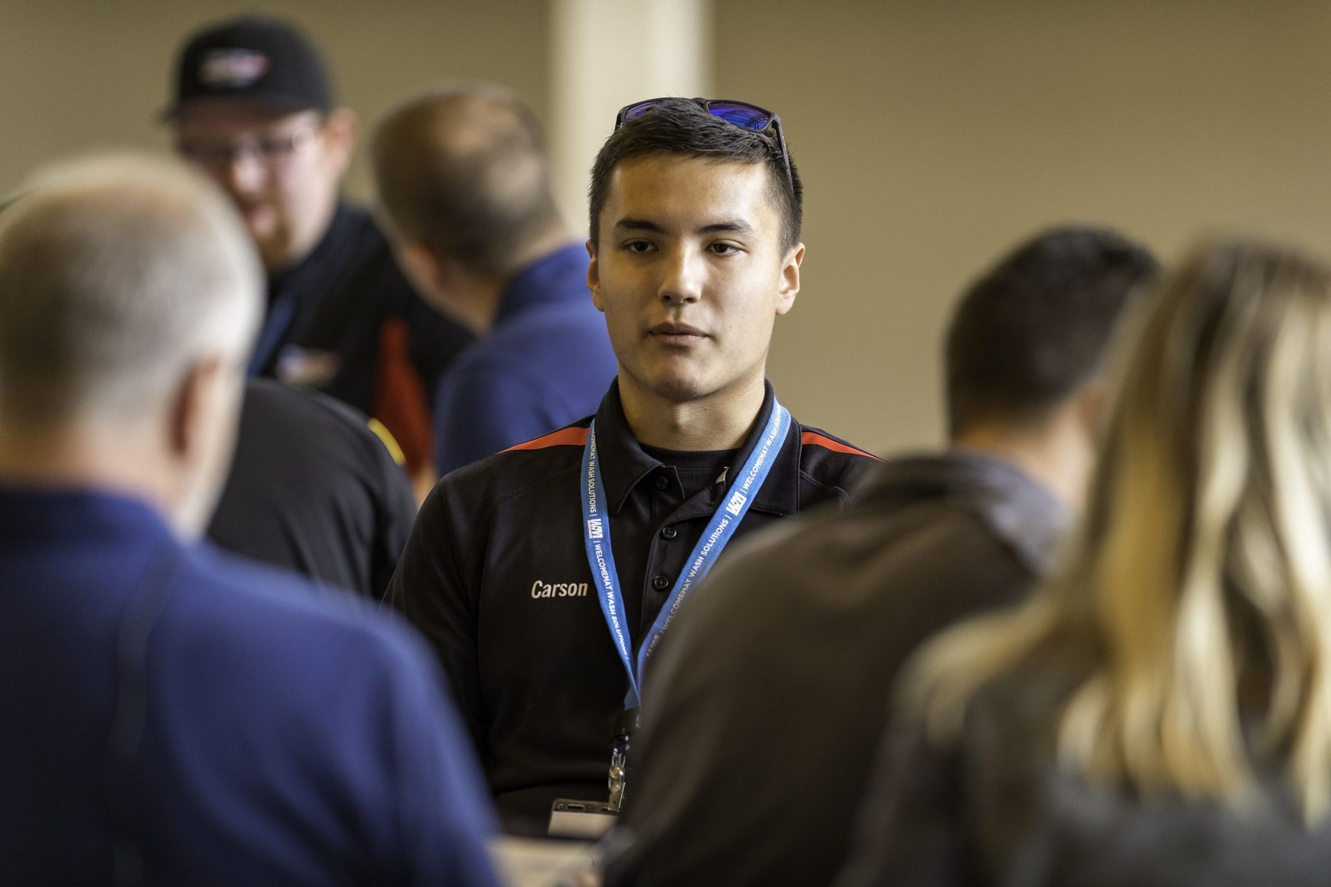 A man with a lanyard around his neck is sitting in a crowd of people.