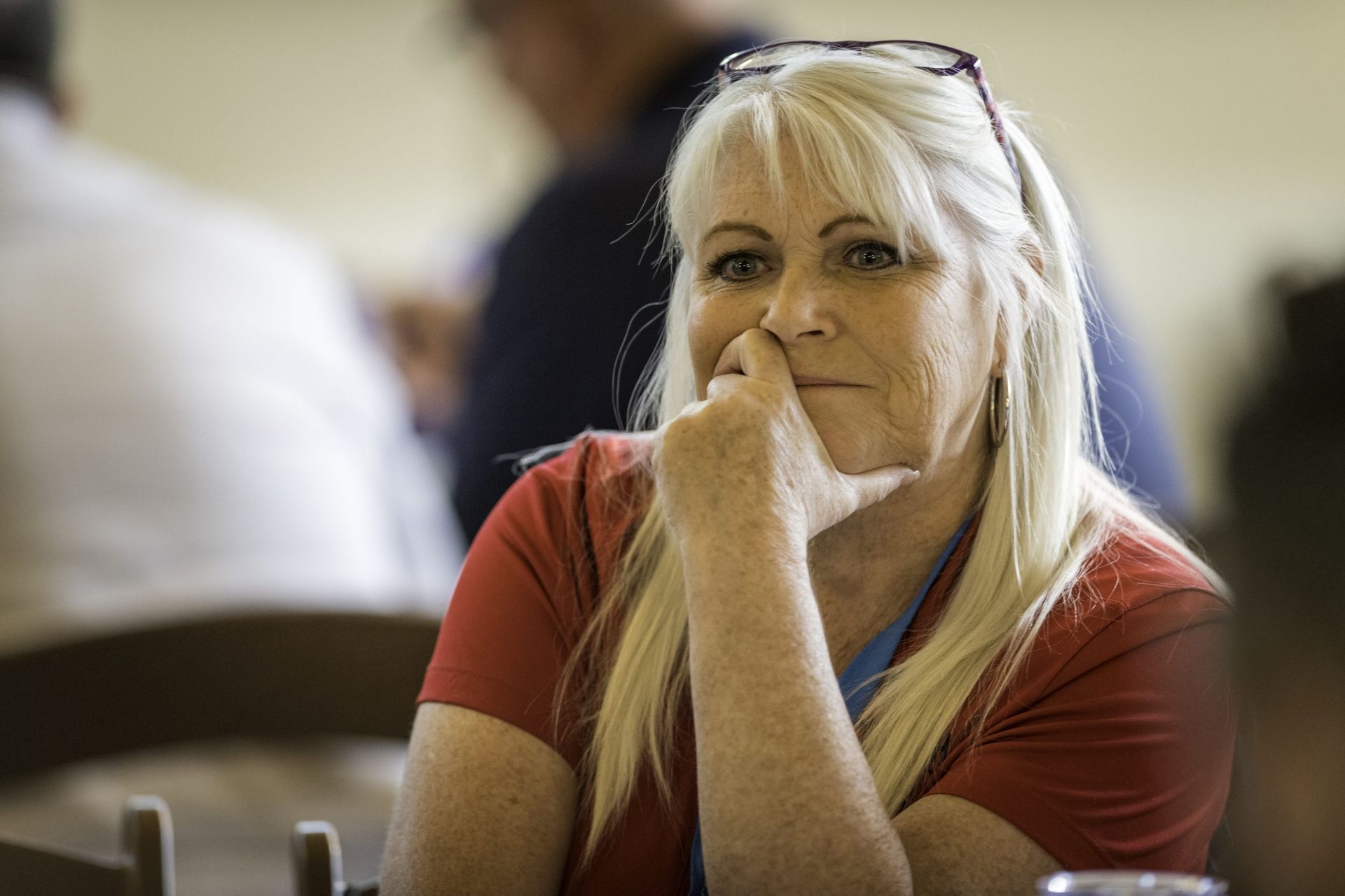 A woman is sitting at a table with her hand on her chin.