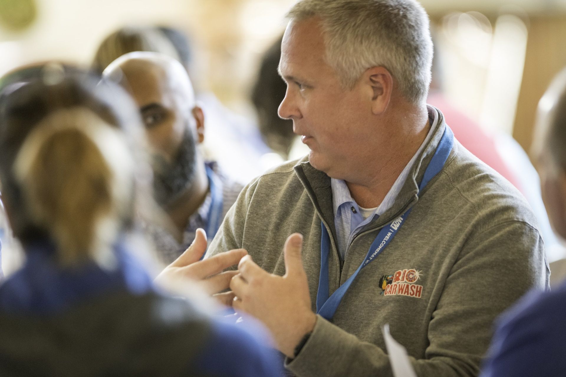 A man in a gray jacket is talking to a group of people.