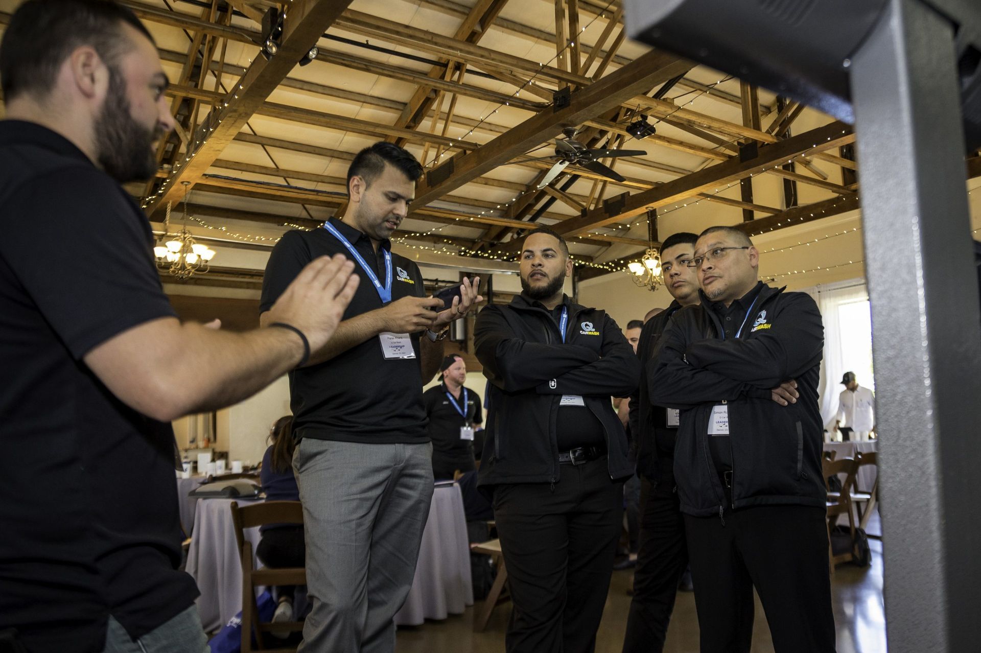 A group of men are standing in a room talking to each other.