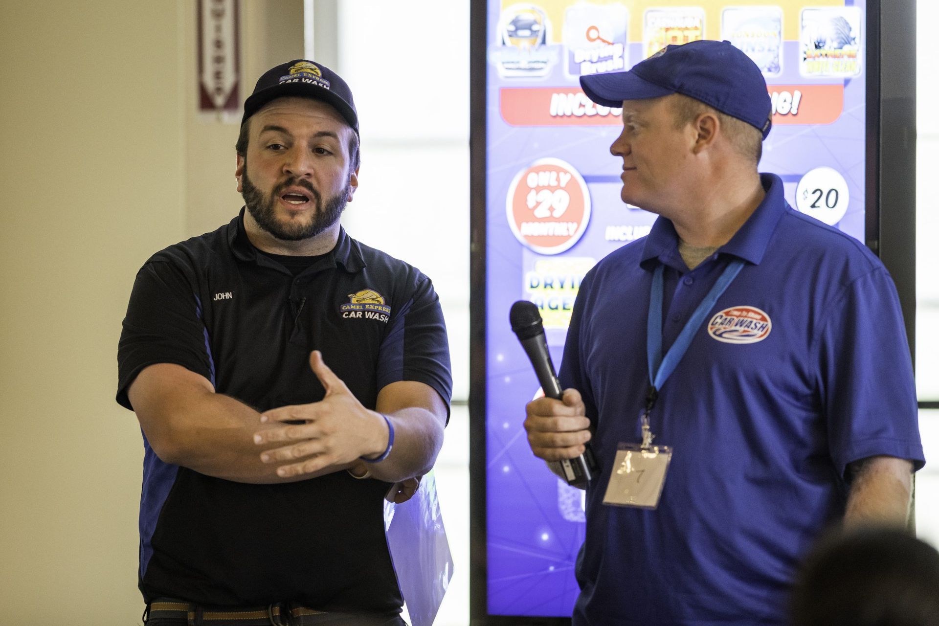 Two men are standing next to each other talking into microphones.