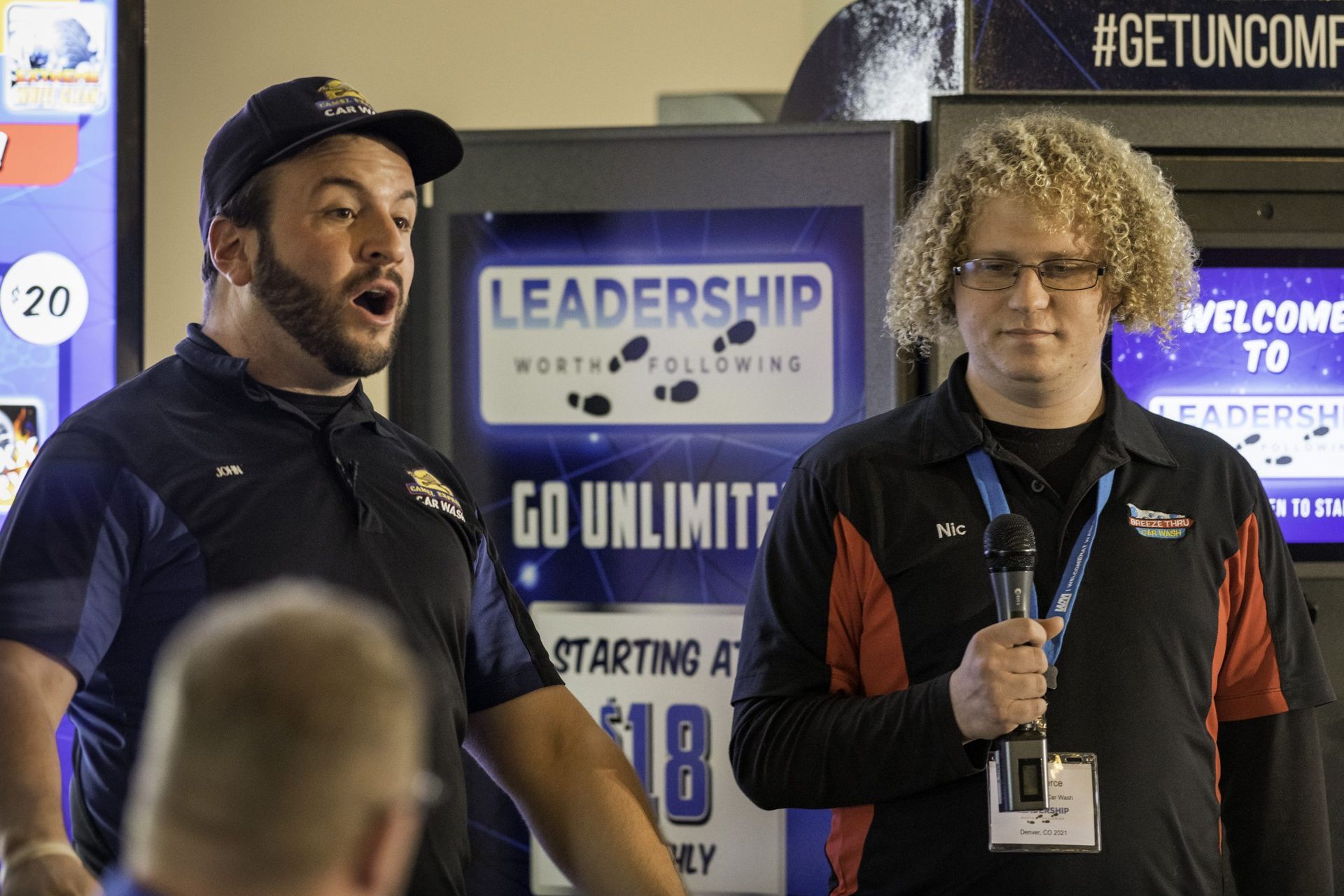 Two men are standing next to each other in front of a sign that says leadership.