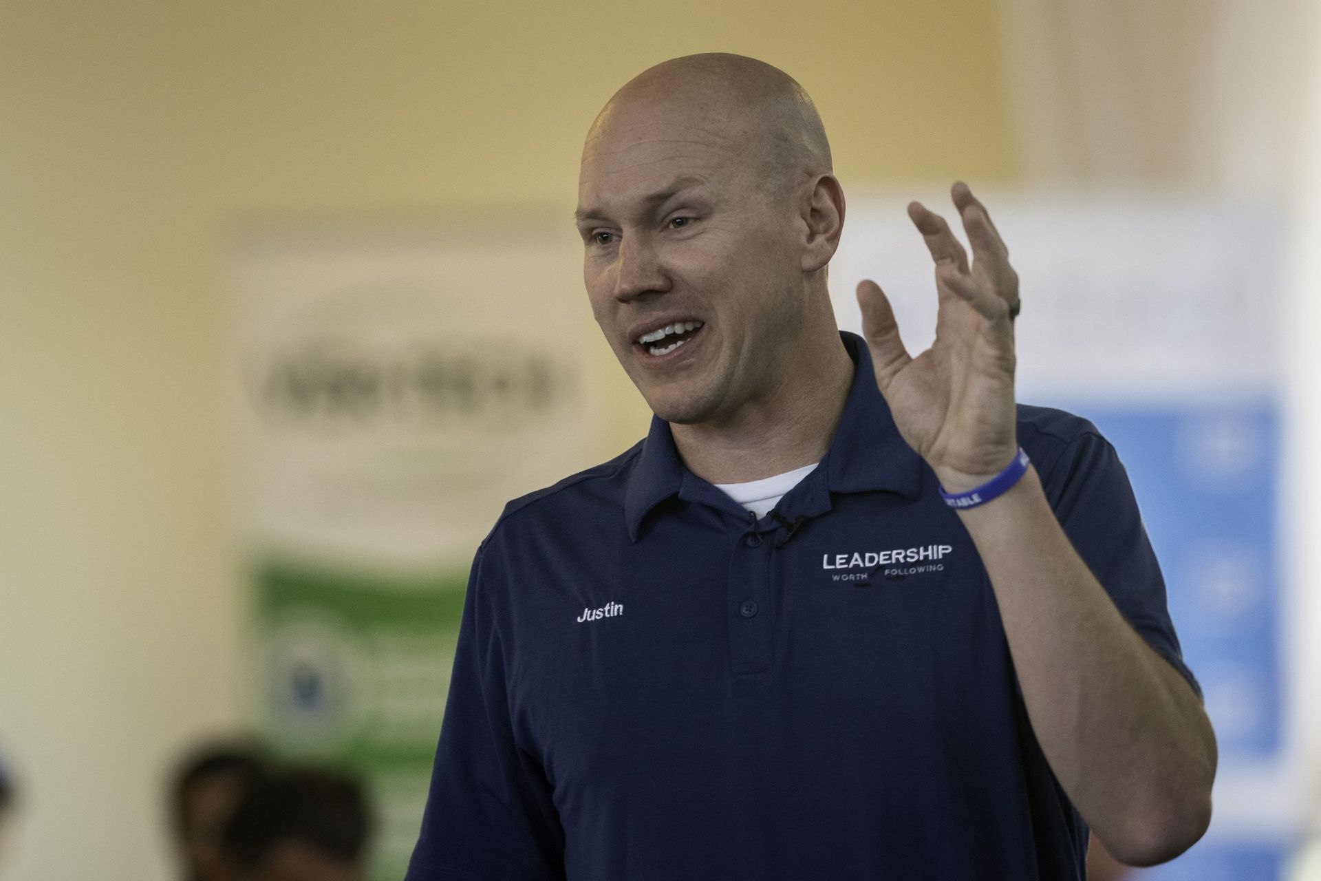 A bald man wearing a blue shirt with the word leadership on it