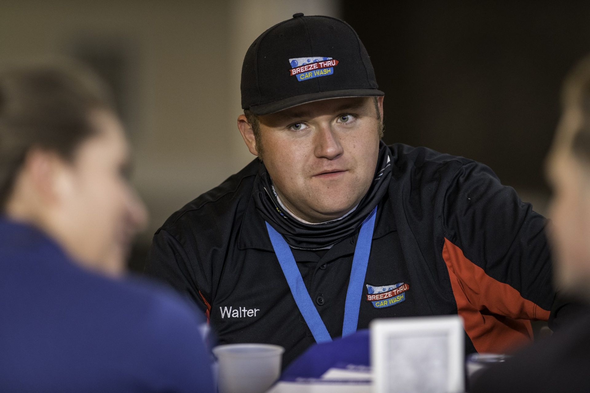 A man in a baseball cap is sitting at a table with other people.