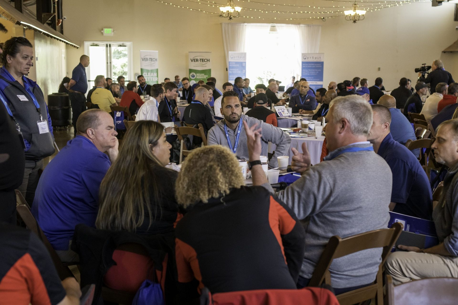 A large group of people are sitting at tables in a large room.