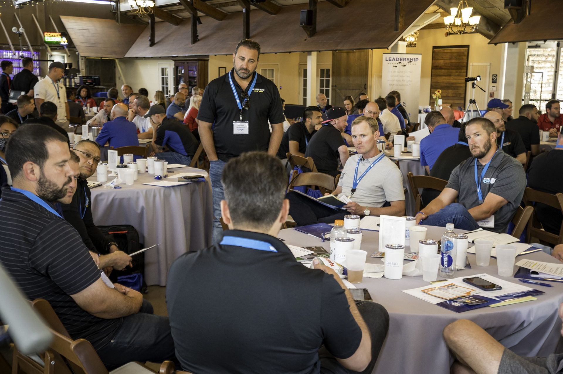 A group of men are sitting at tables in a room.