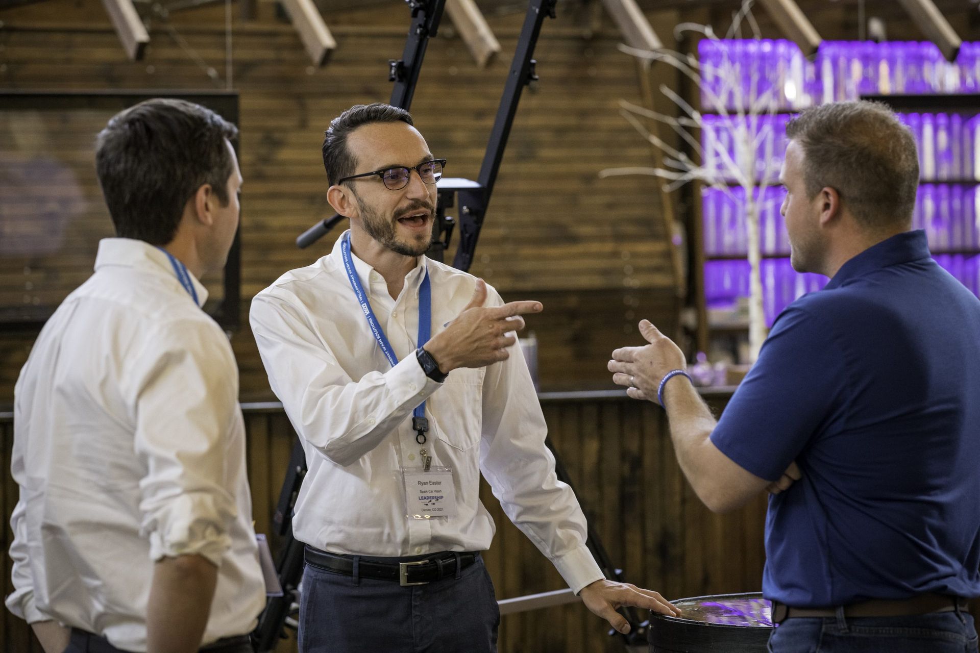 Three men are talking to each other in a room.