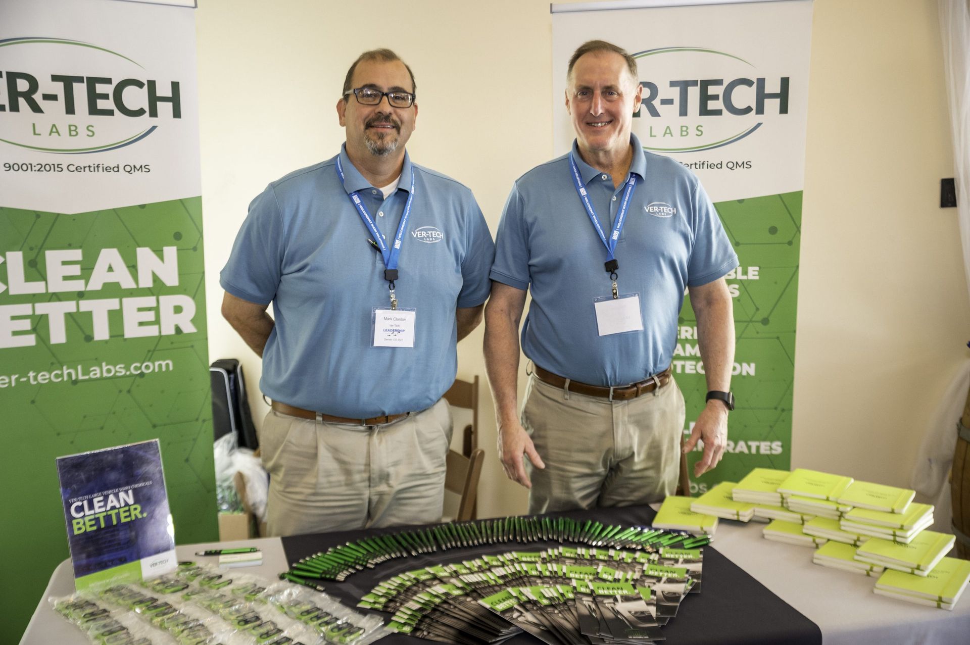Two men are standing next to each other in front of a table.