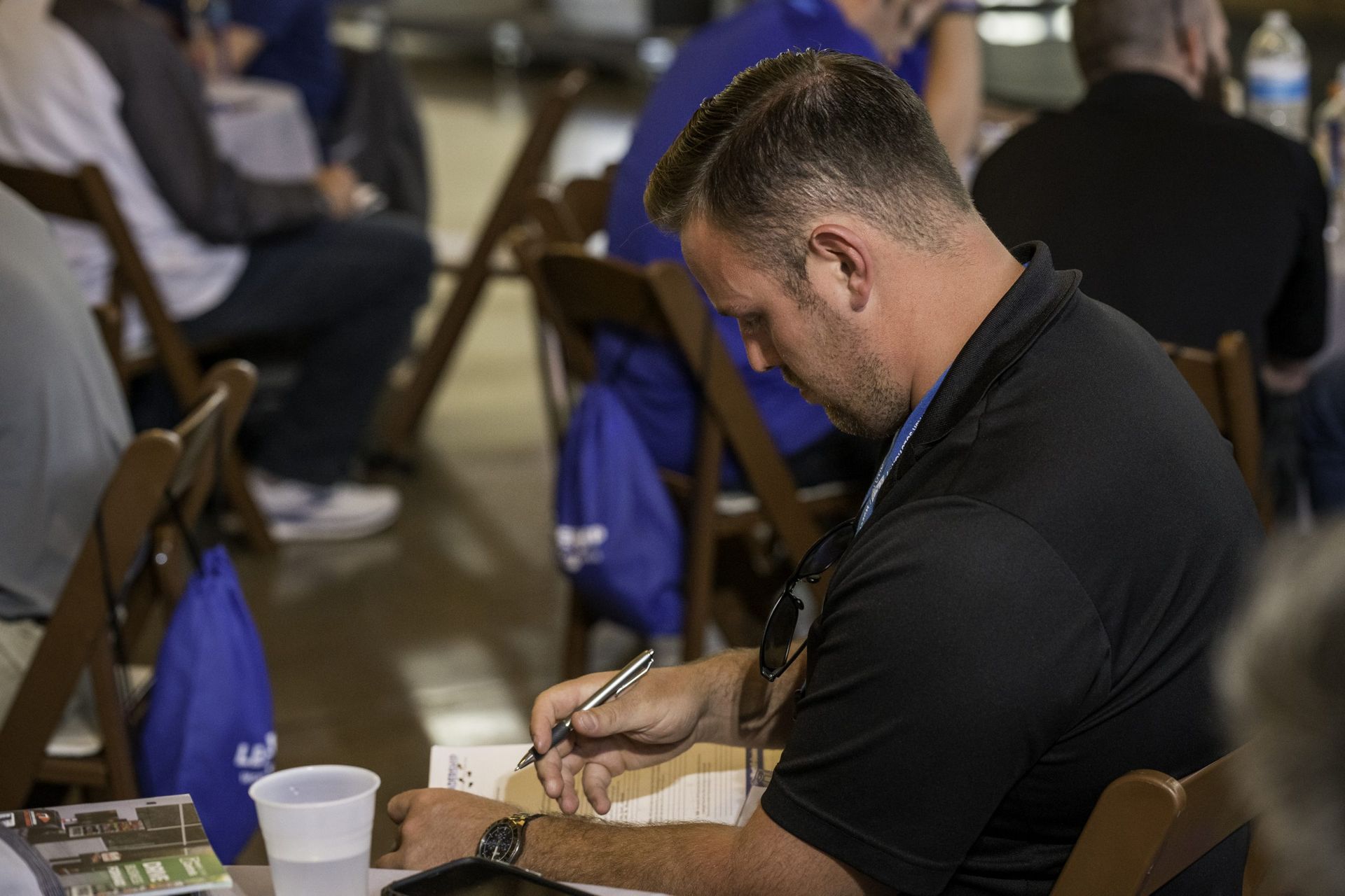 A man is sitting at a table writing on a piece of paper.