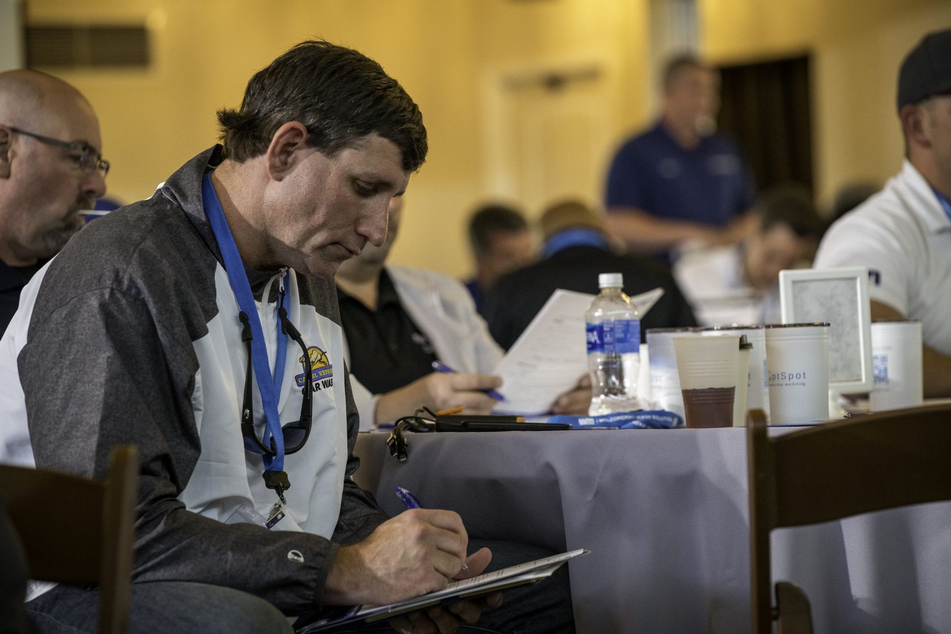 A man is sitting at a table writing on a clipboard.