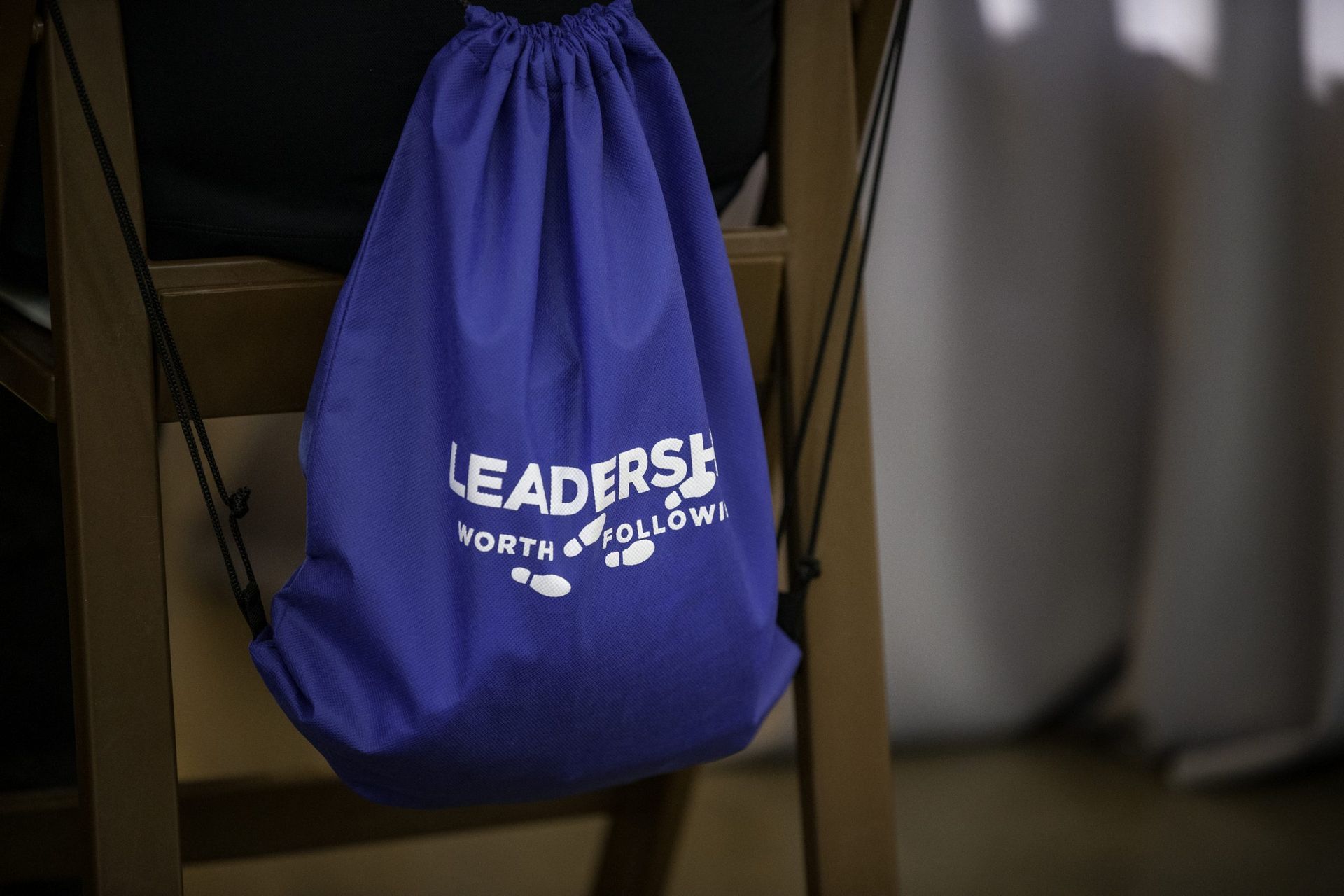 A purple drawstring bag is sitting on a wooden chair.