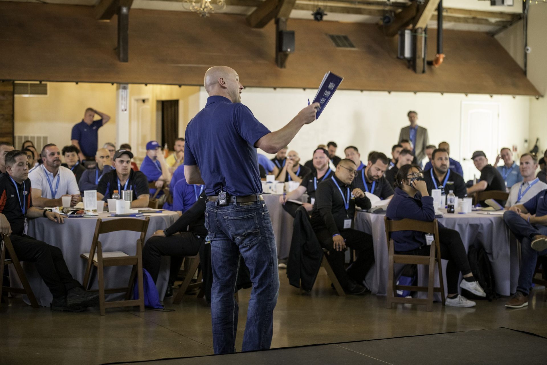 A man is giving a presentation to a group of people sitting at tables.