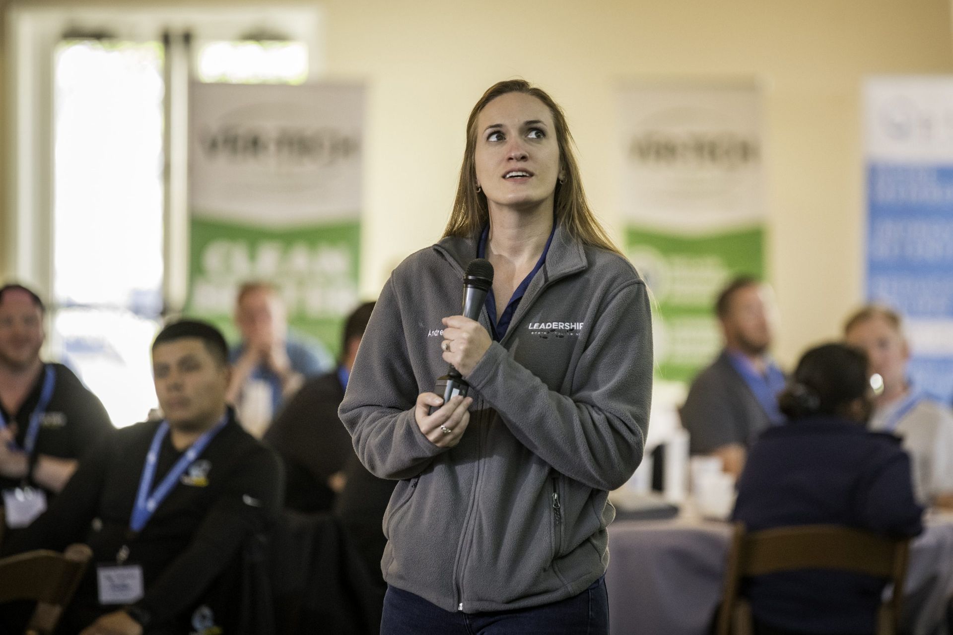 A woman is holding a microphone in front of a group of people.