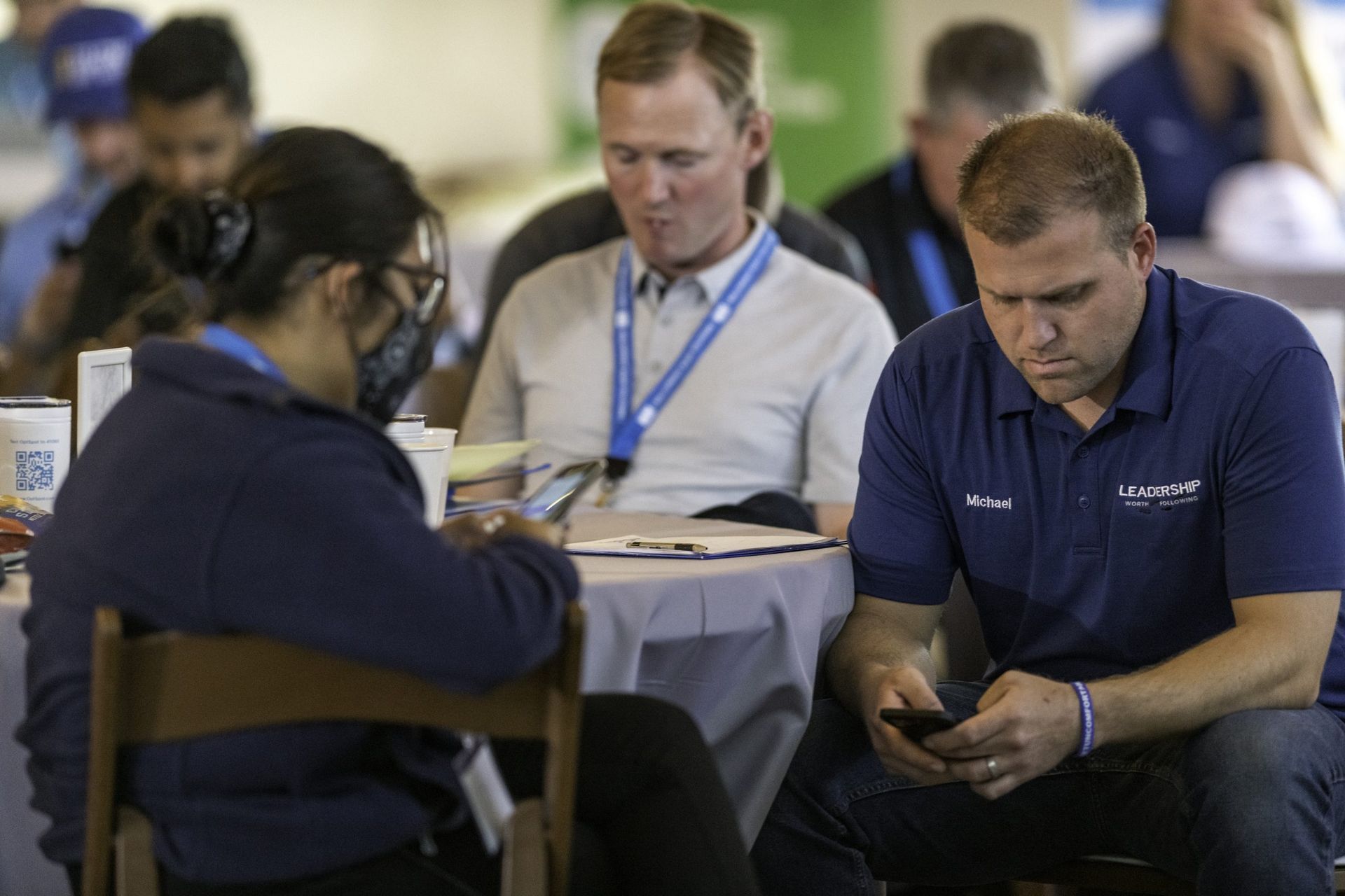 A group of people are sitting at a table looking at their phones.