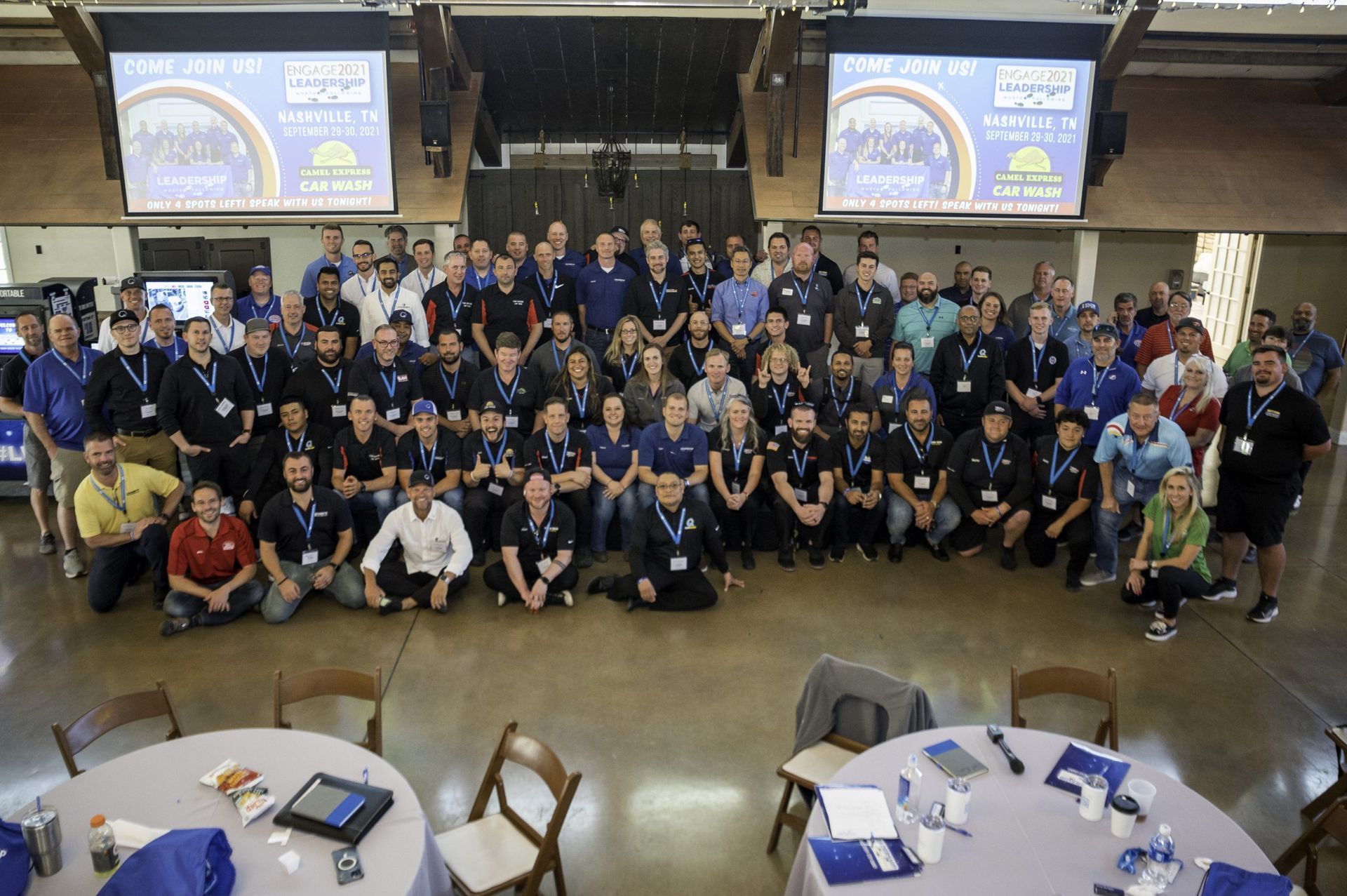 A large group of people are posing for a picture in a room with tables and chairs.