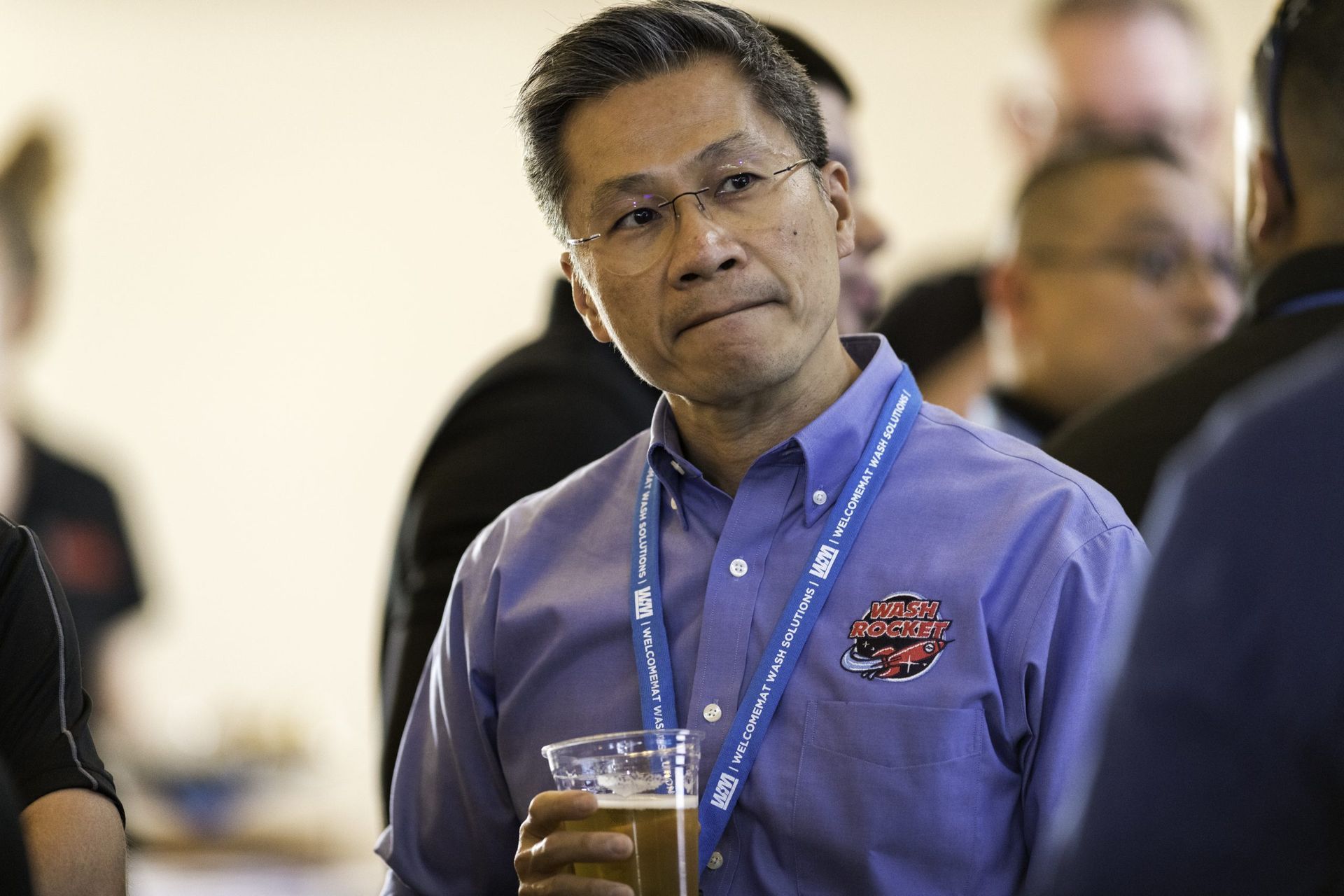 A man in a blue shirt is holding a glass of beer.