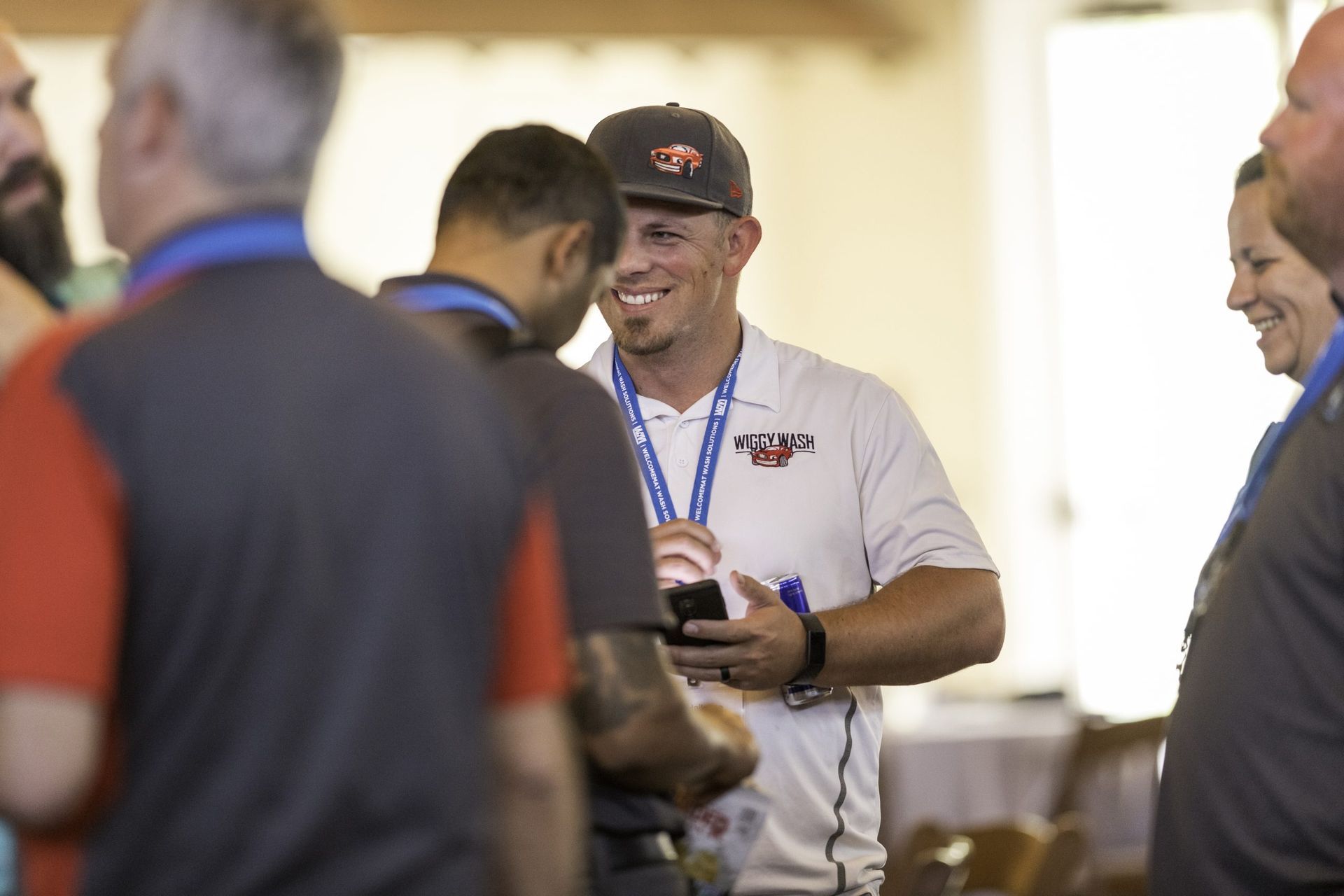 A group of people are standing around a man holding a cell phone.