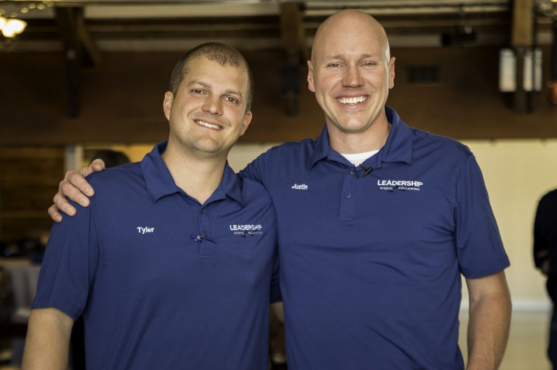 Two men in blue shirts are posing for a picture together.
